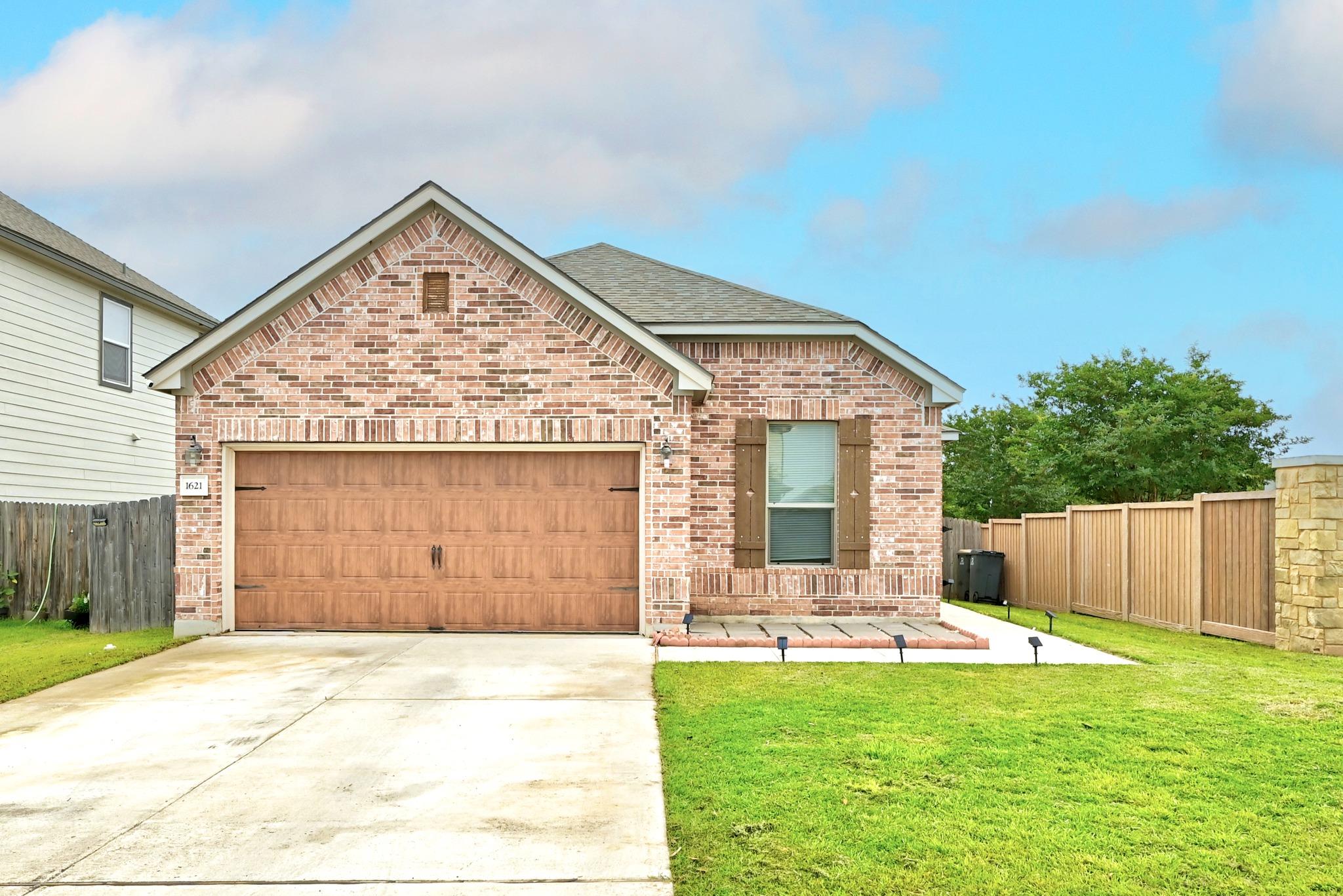 Brick facade home featuring a wood-finish garage 