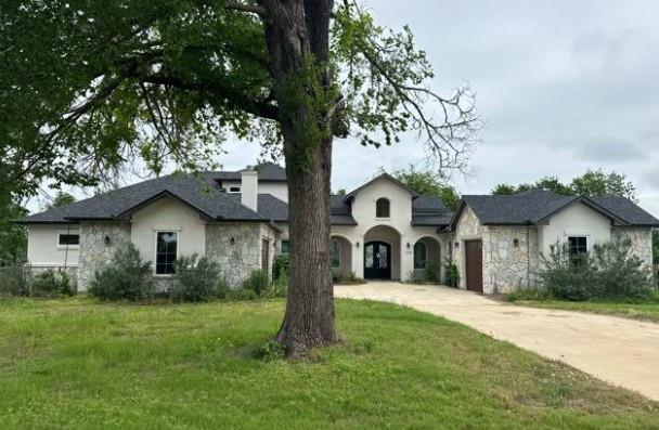 Stucco and stone exterior featuring a prominent a