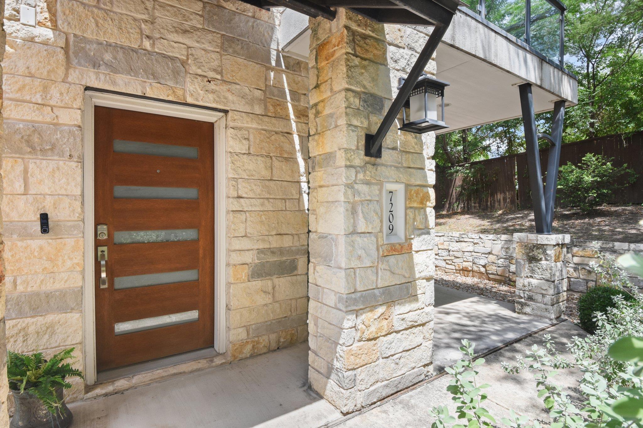 A modern entry features warm wood, horizontal gla