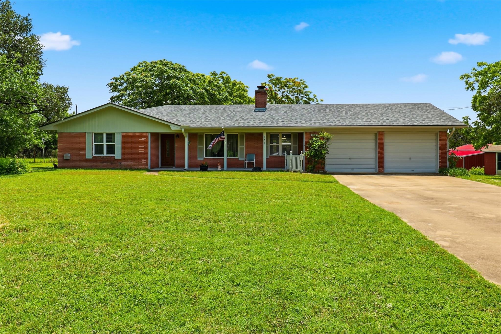 Brick facade home featuring a wide driveway and v