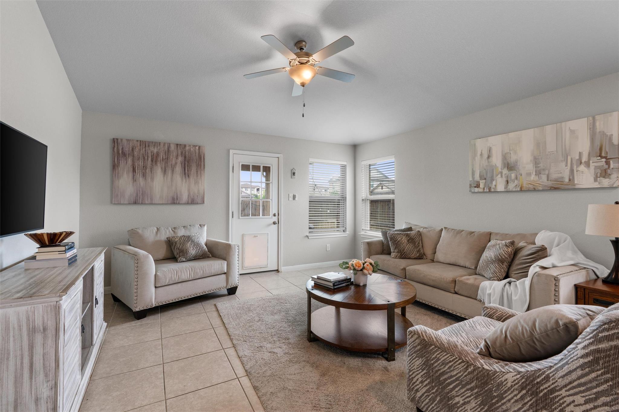 Open-concept living area featuring light-toned ti