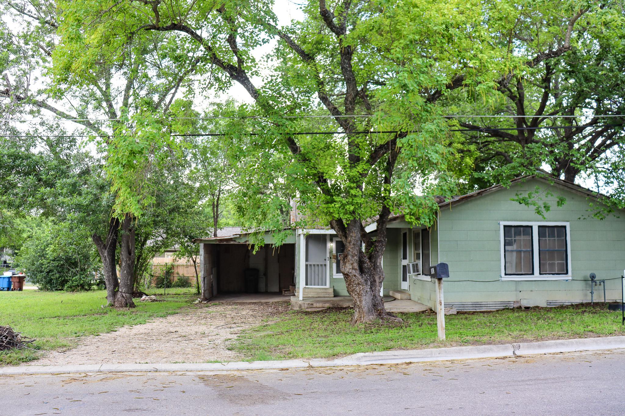Mature trees shade this modest home, presenting a