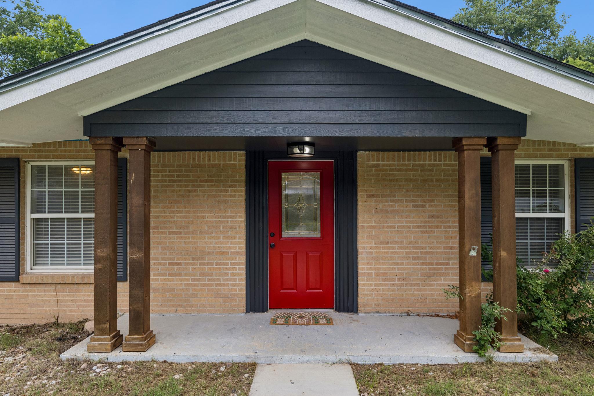 A vibrant red entry door with decorative glass we