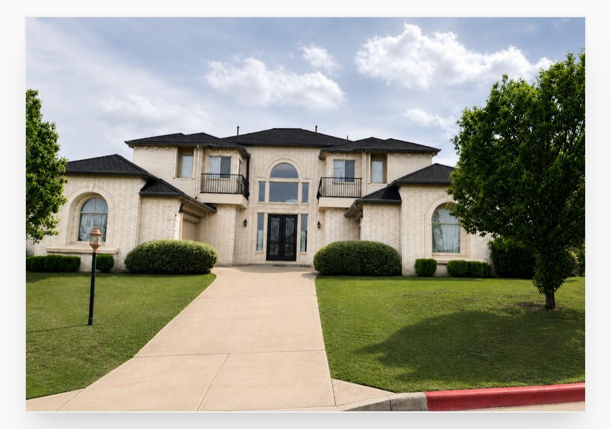 A grand white brick residence features a sweeping