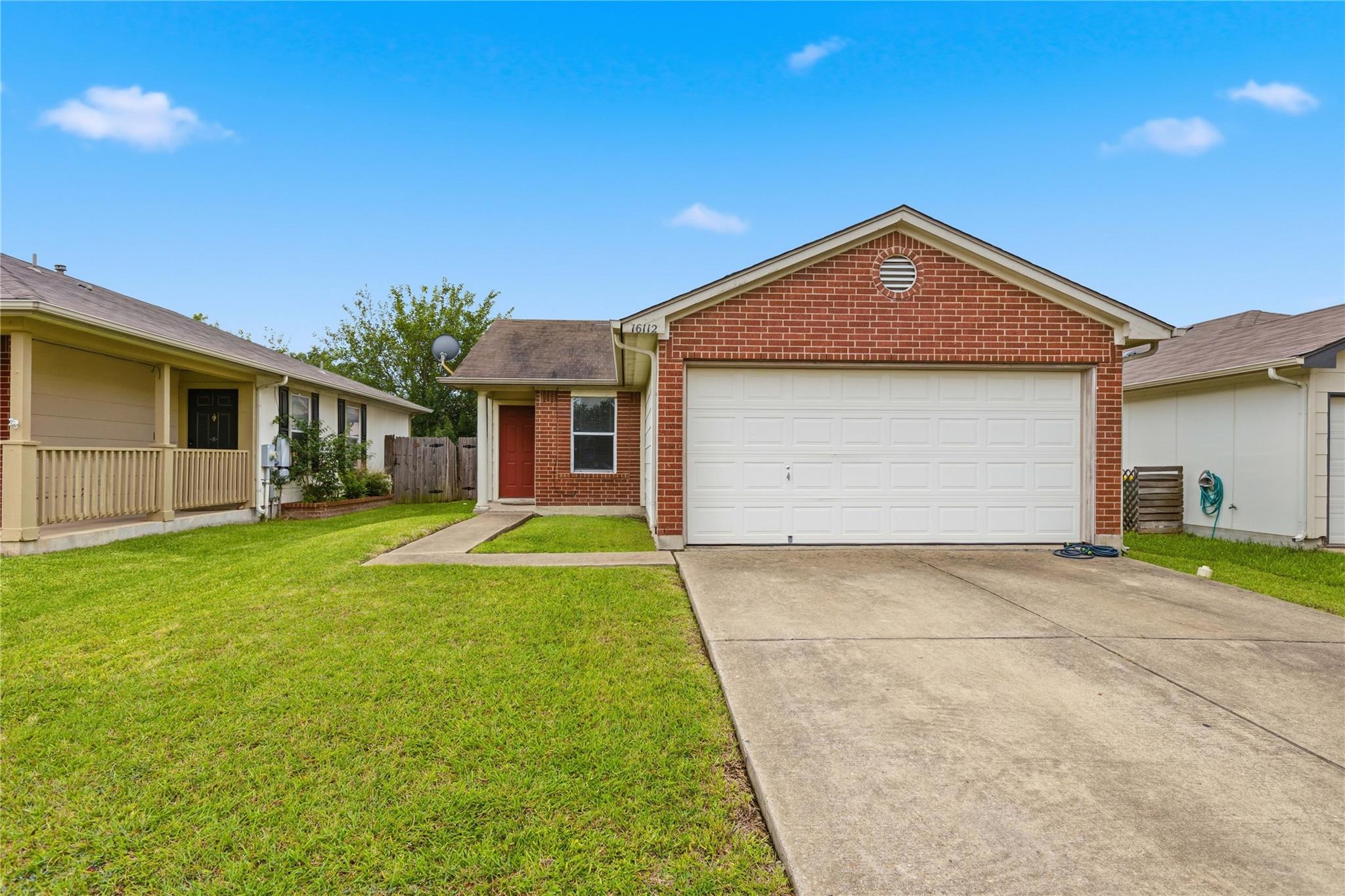 Brick exterior featuring a two-car garage, a conc