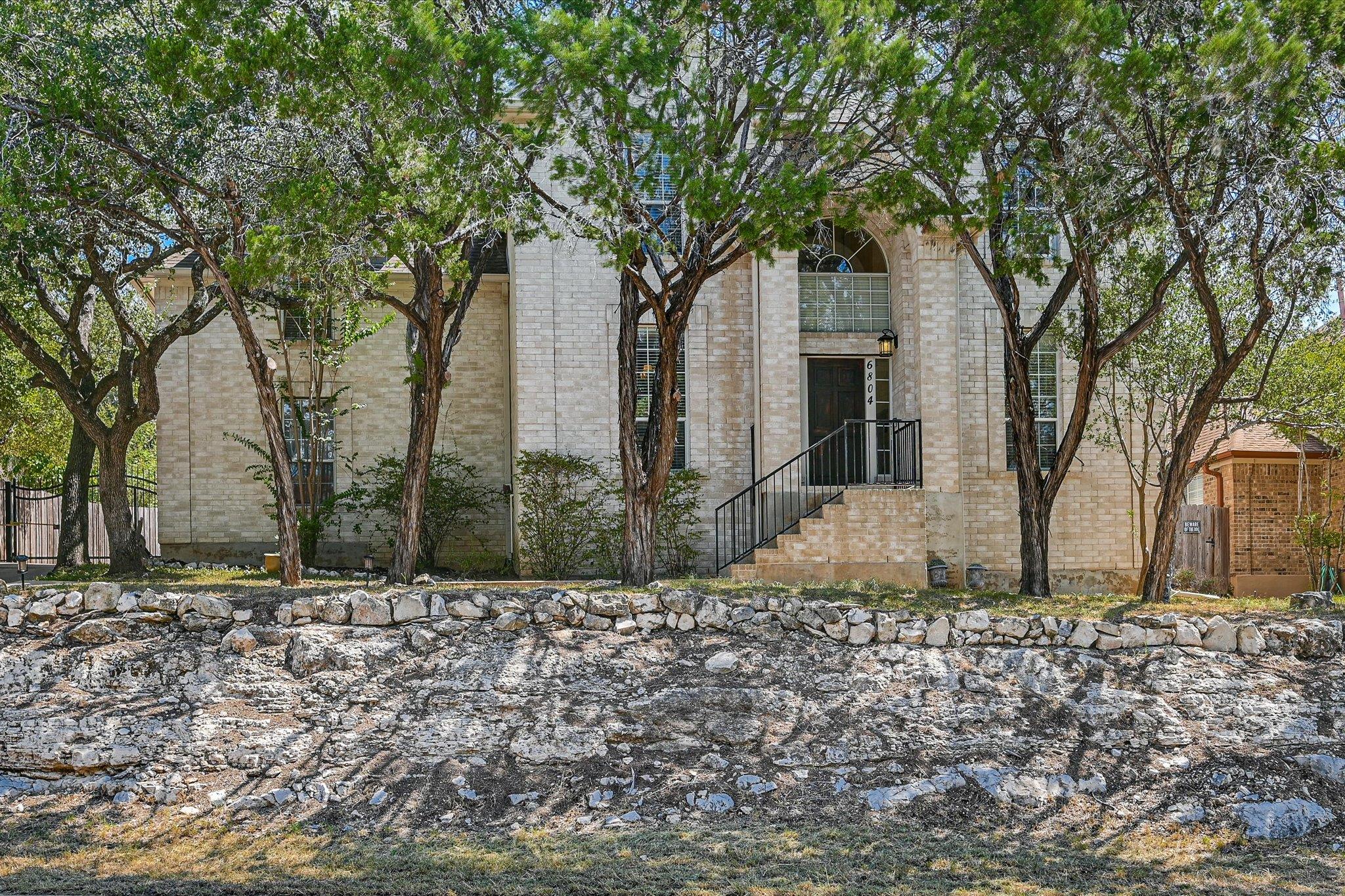 Mature trees shade a classic brick facade sitting