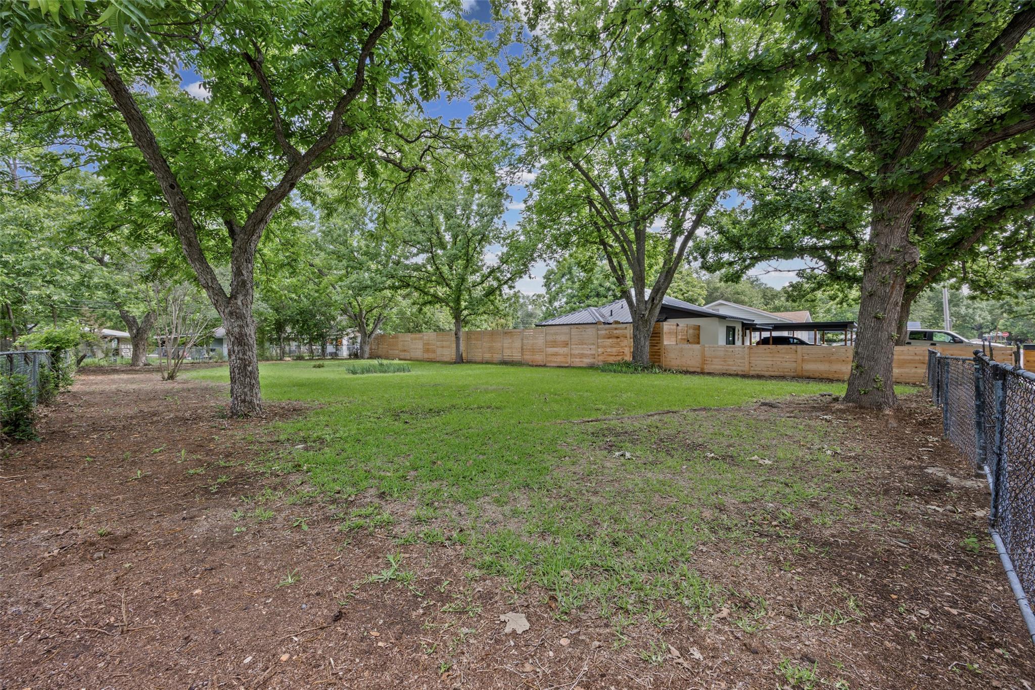 A spacious backyard with mature shade trees, offe