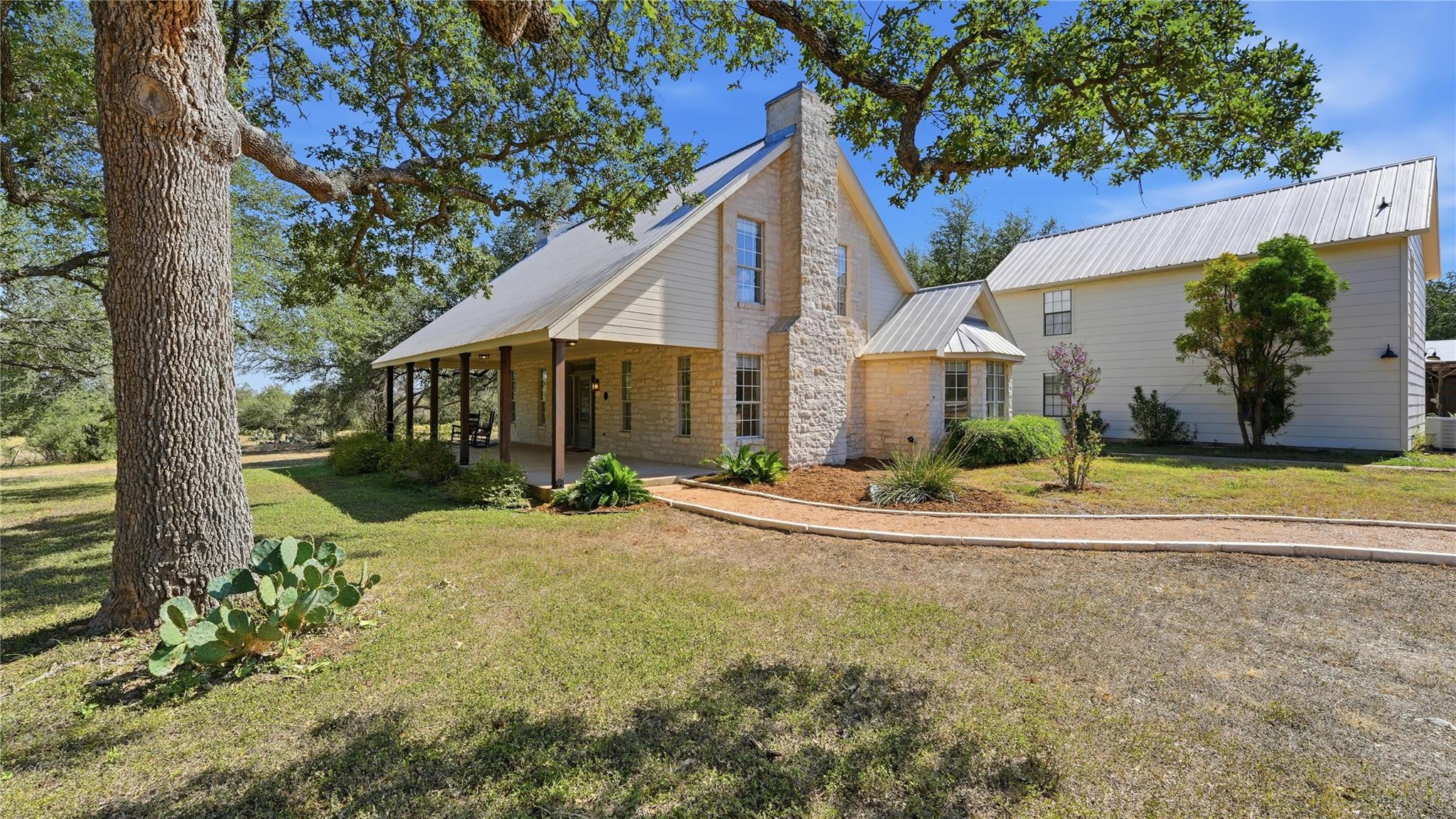 Mature shade trees frame a classic stone fireplac