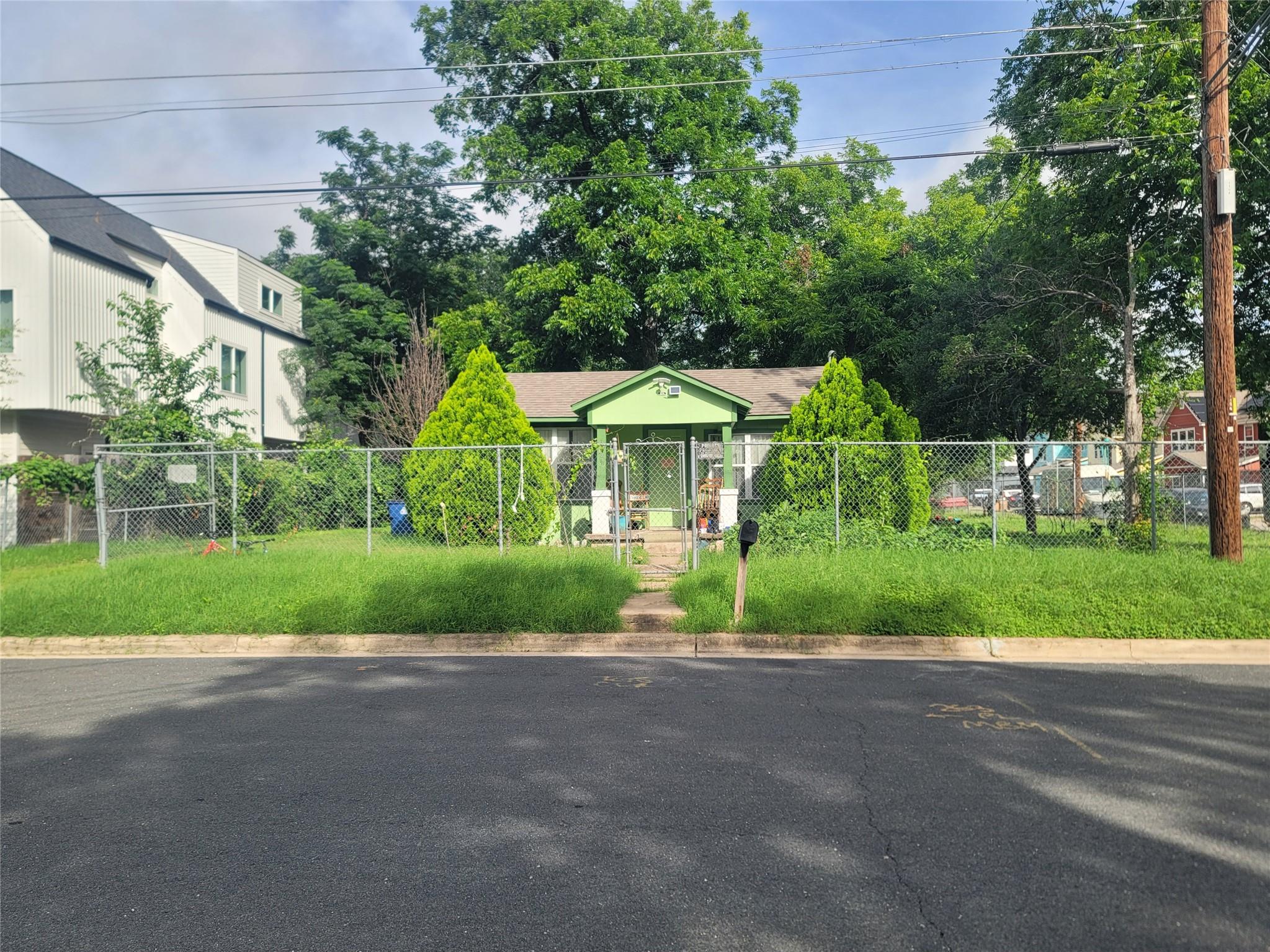 A fenced front yard with lush greenery offers a q