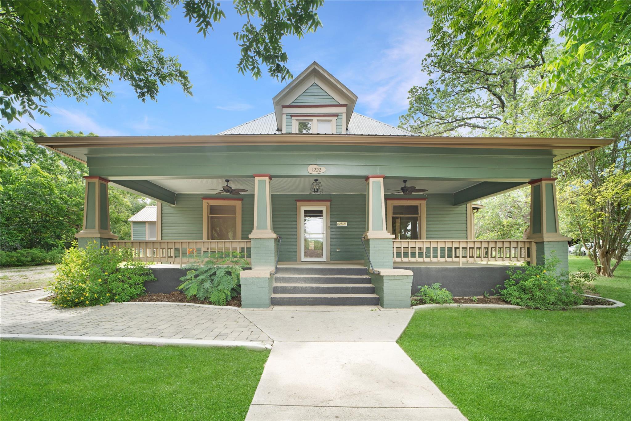 A classic green-sided residence features a welcom