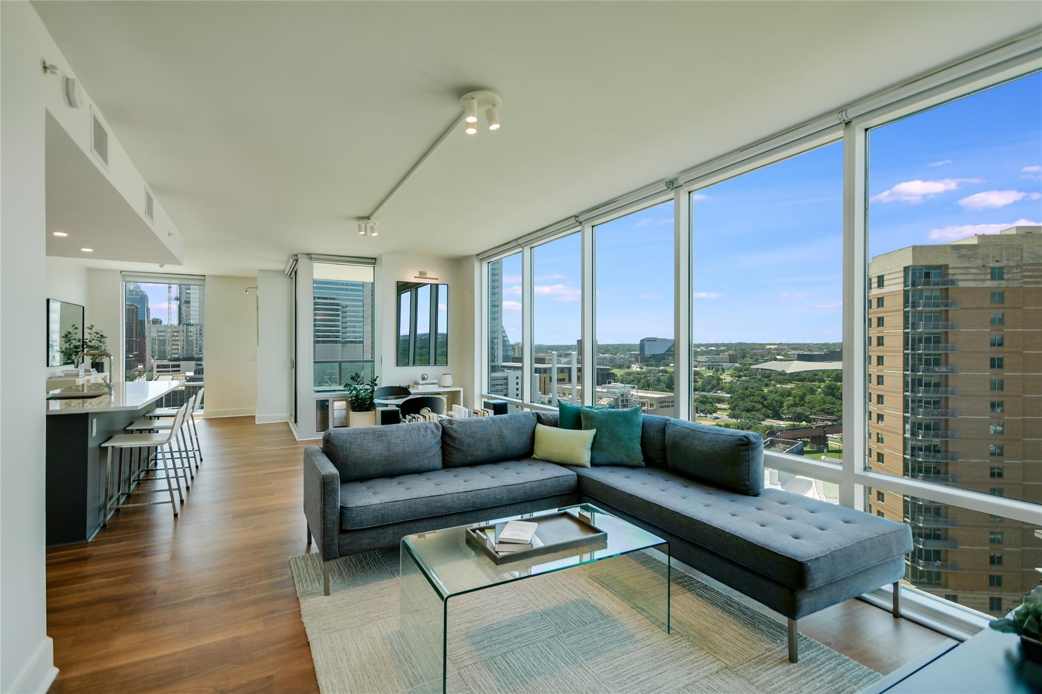 Floor-to-ceiling windows frame verdant urban pano