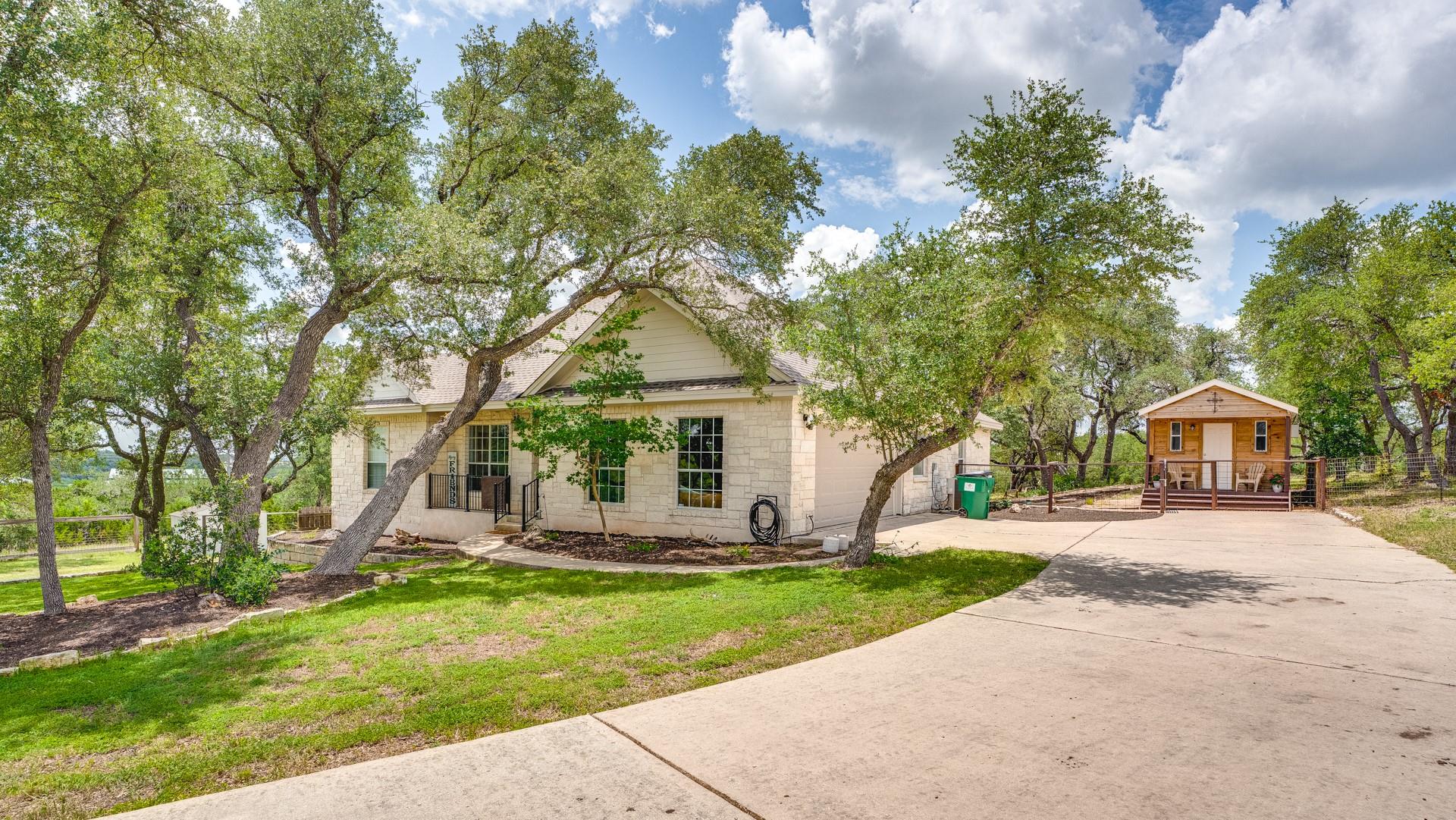 Mature trees frame a charming home with a separat