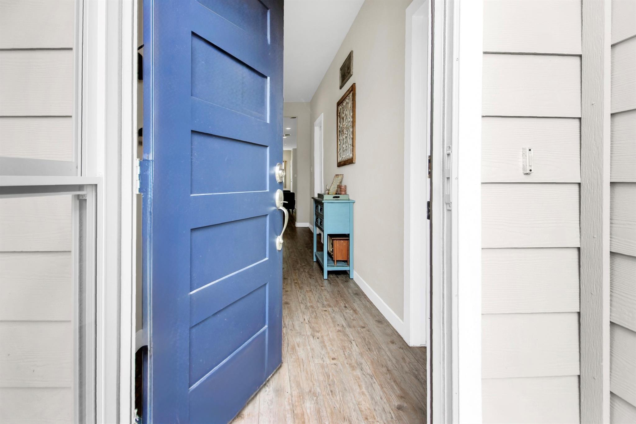 A vibrant blue door welcomes you into a long, bri