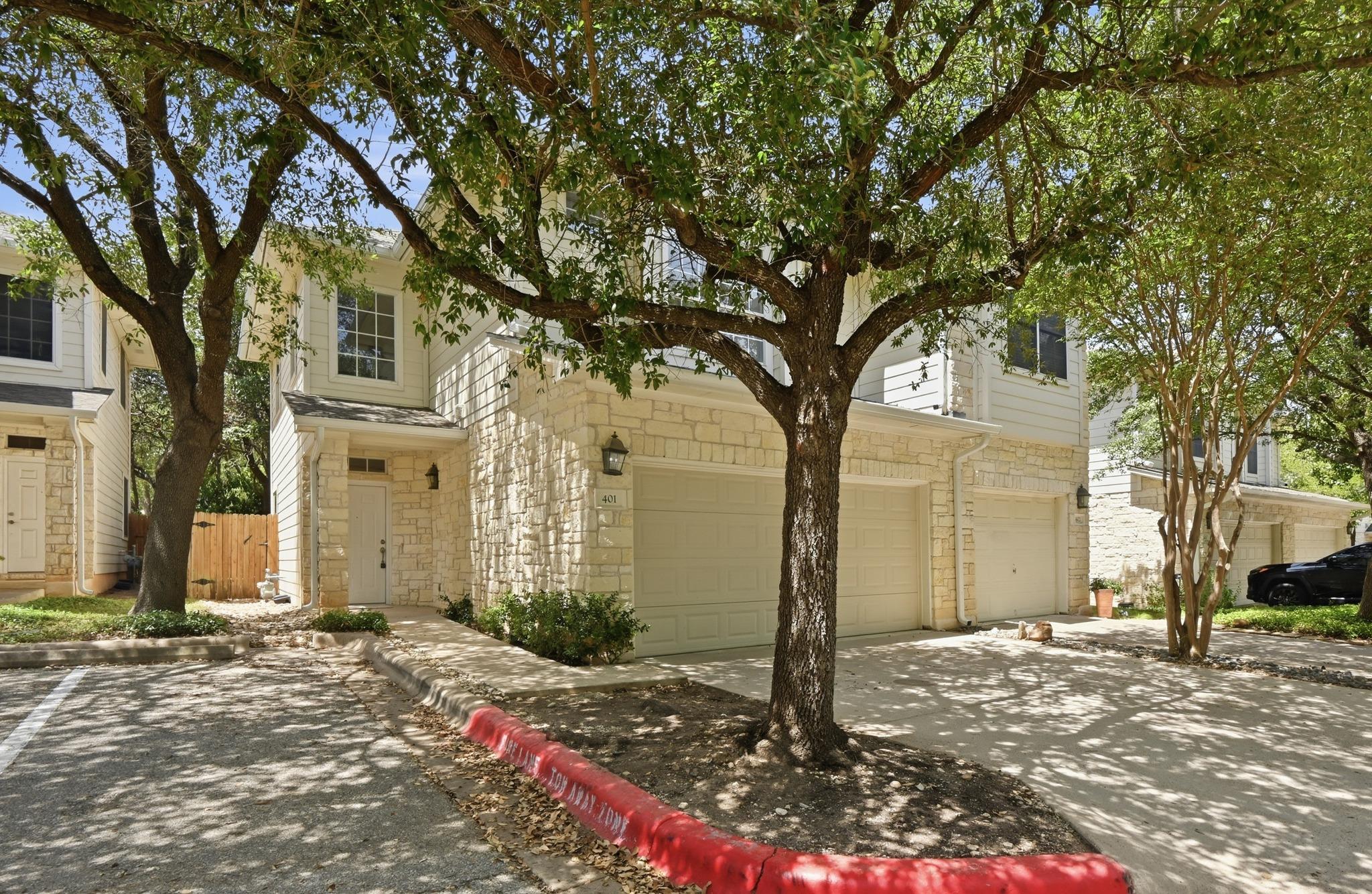 Shade trees frame a classic stone and siding exte
