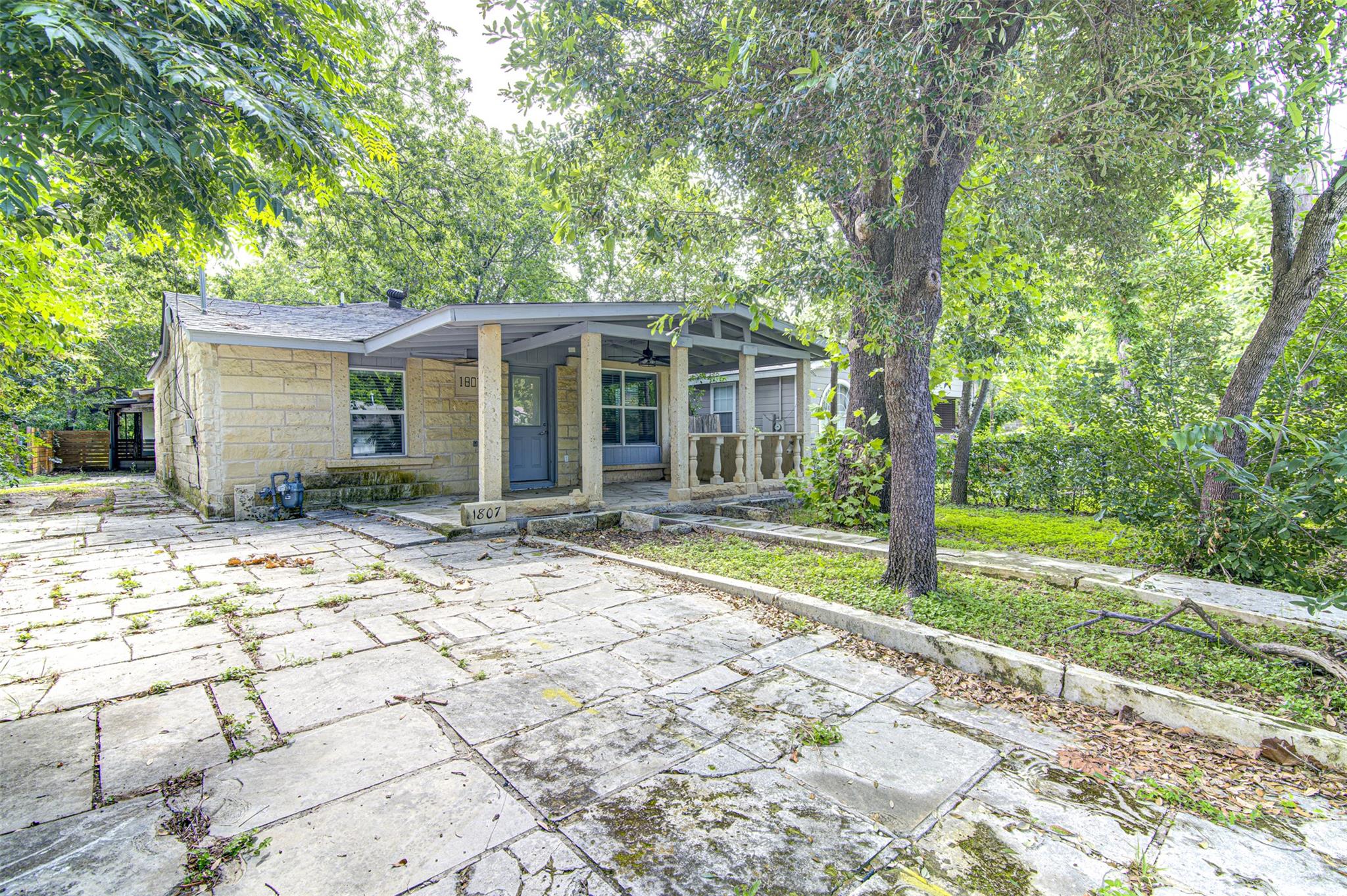 Mature trees frame a cozy stone home, featuring a