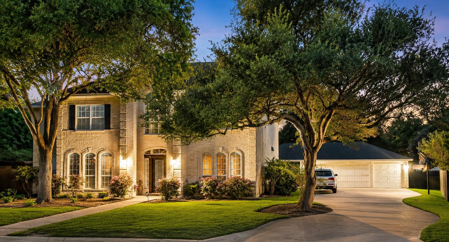 Mature trees frame a charming home with a winding