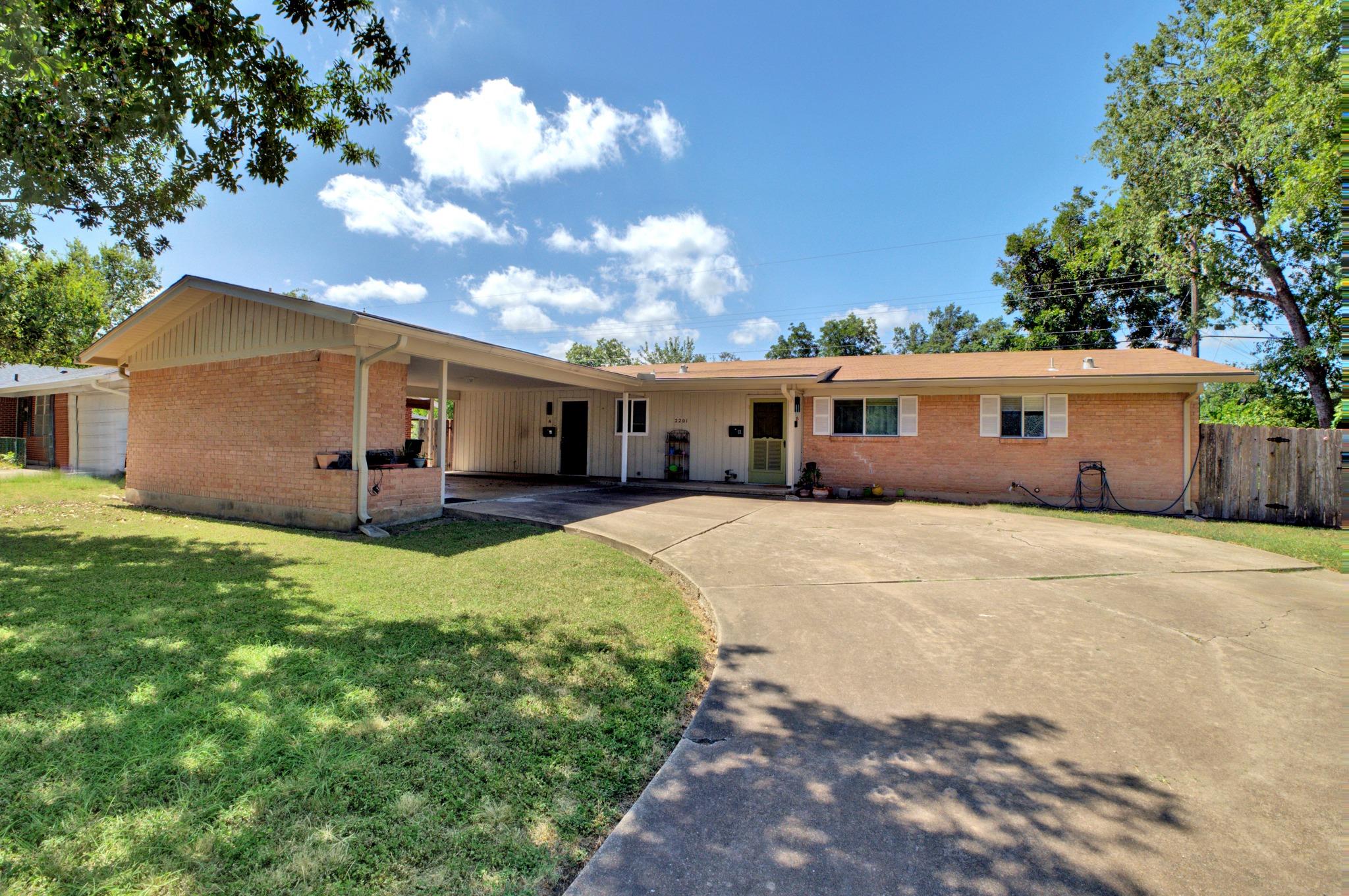 A spacious concrete driveway leads to this classi