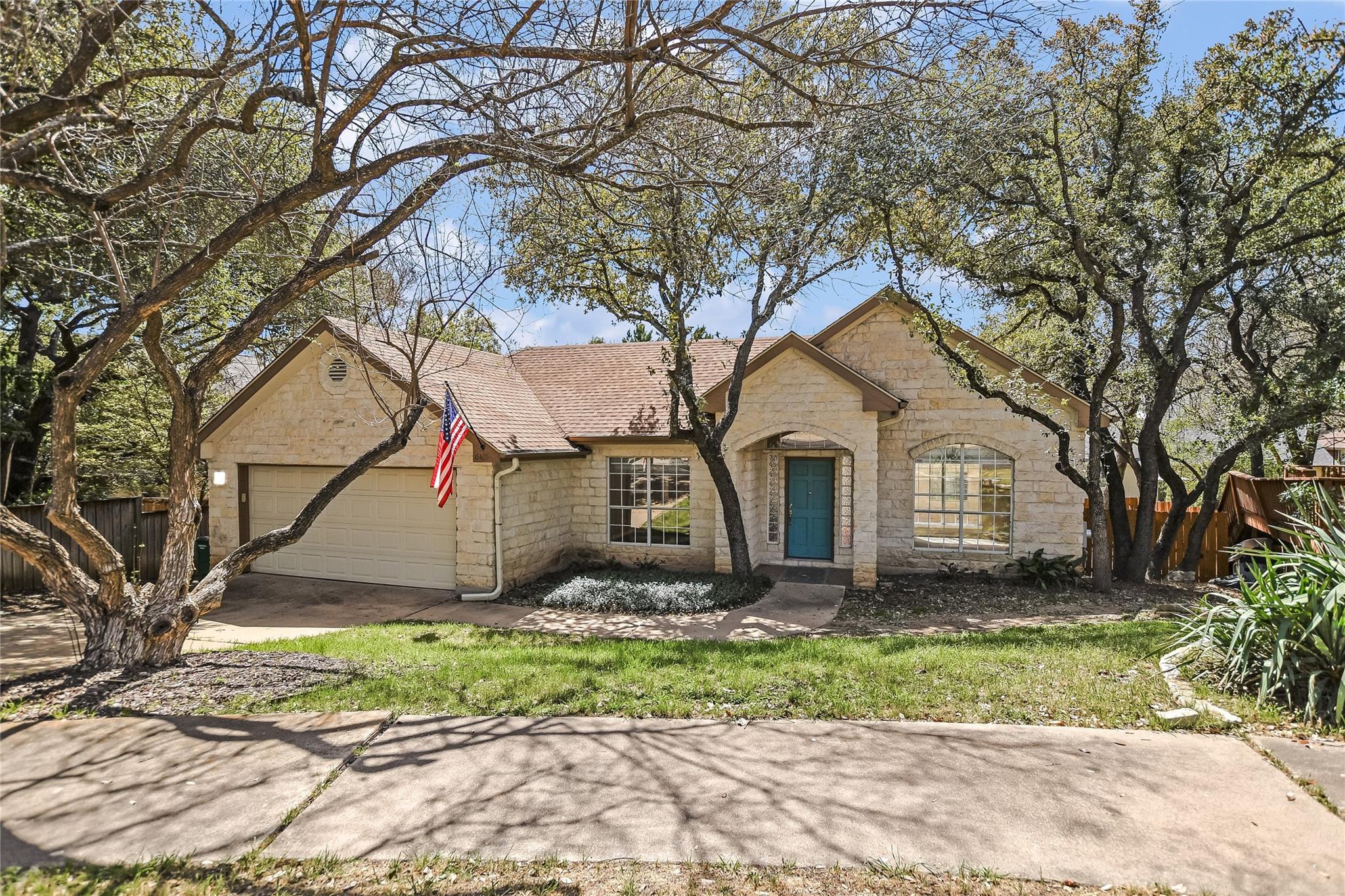 Mature trees frame this charming stone-clad resid