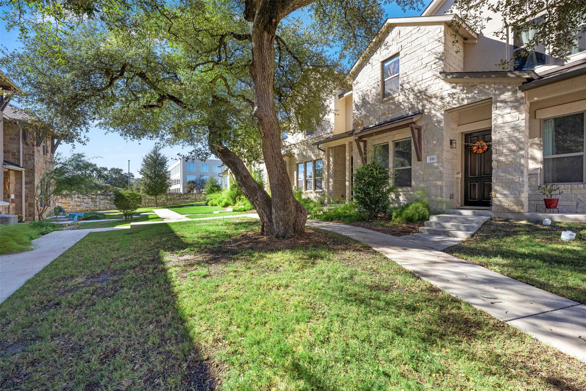 A graceful oak tree shades the stone facade of th
