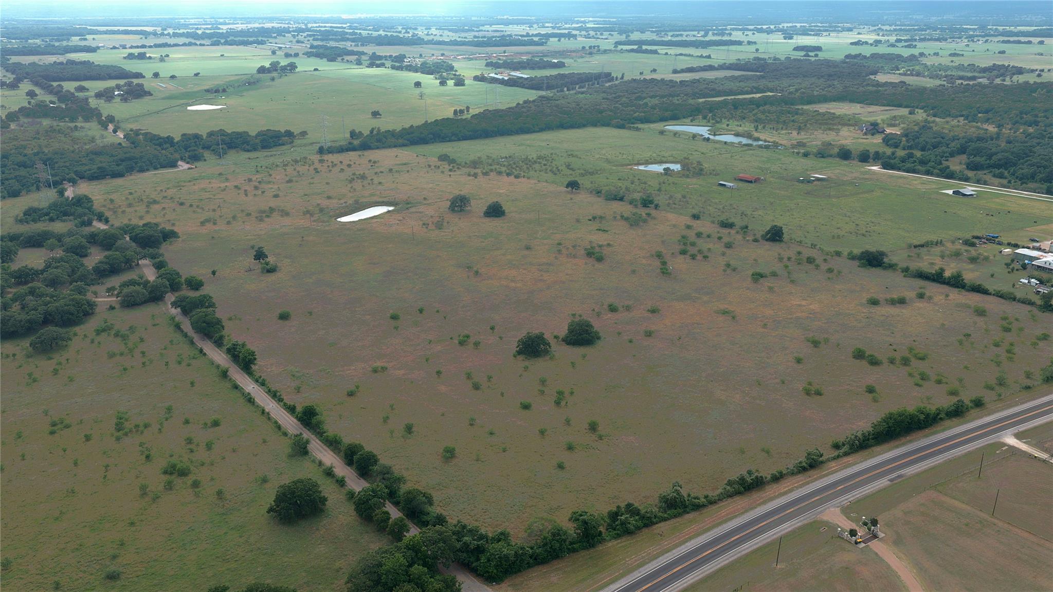 Vast acreage unfolds with verdant fields, scatter