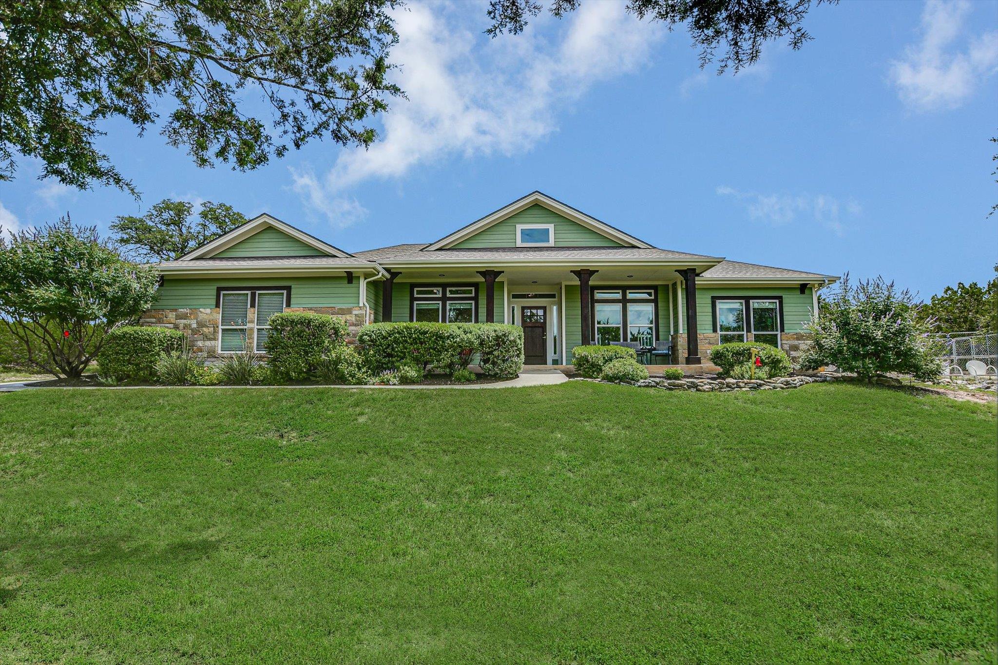 Green siding and stone accents welcome you to thi
