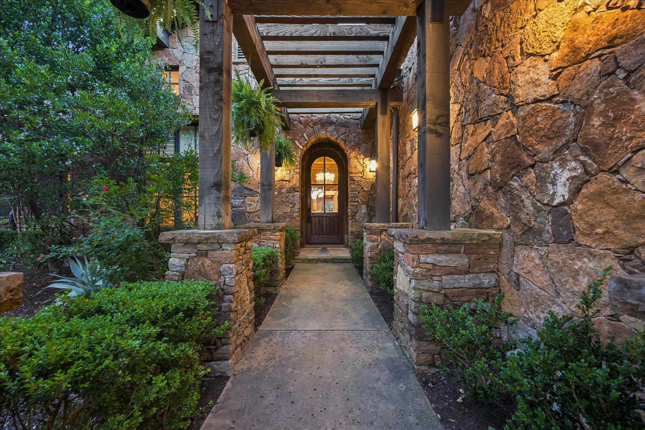 An inviting stone-clad entry features an arched w