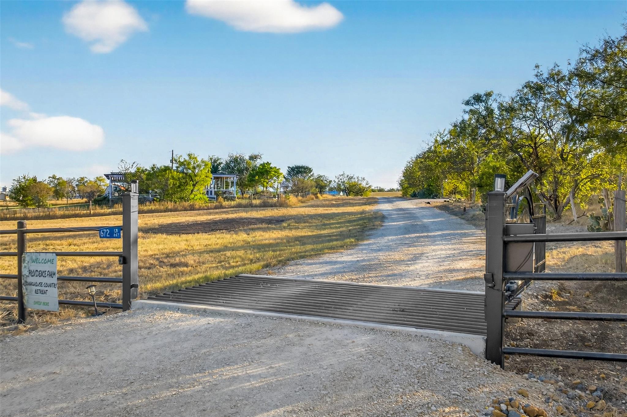 A private gravel driveway with a cattle guard lea
