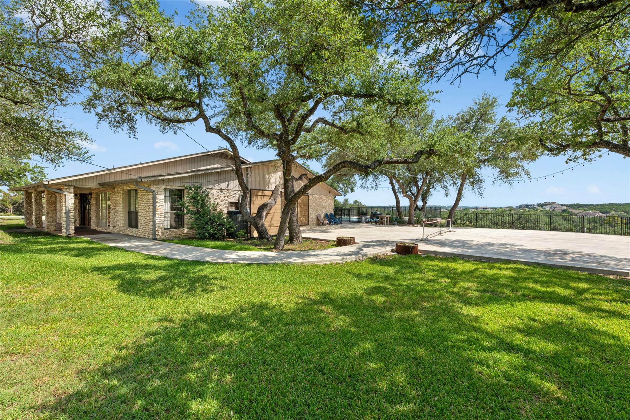 Mature trees shade this inviting front yard, offe