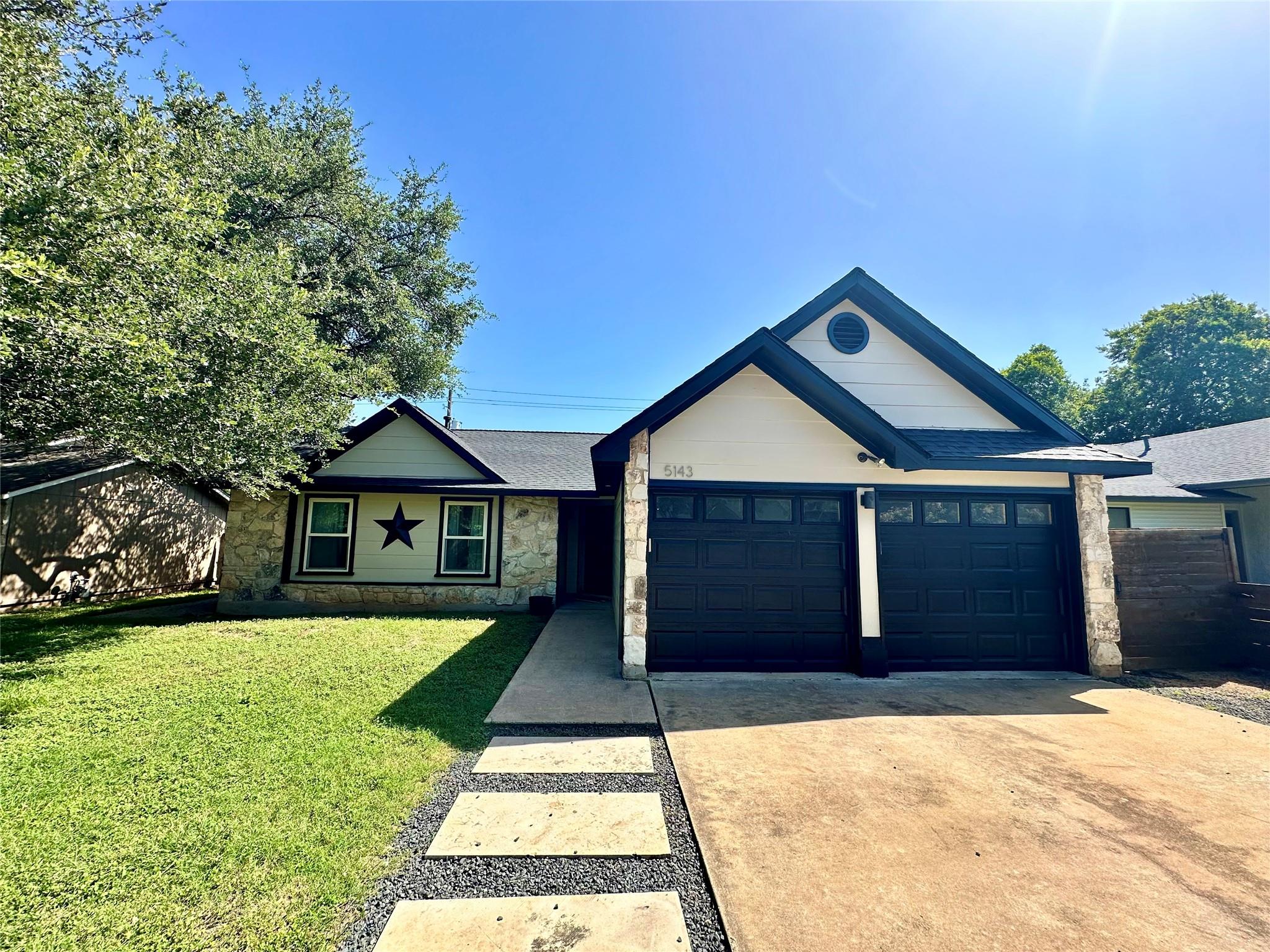 A welcoming stone facade and twin garage doors de