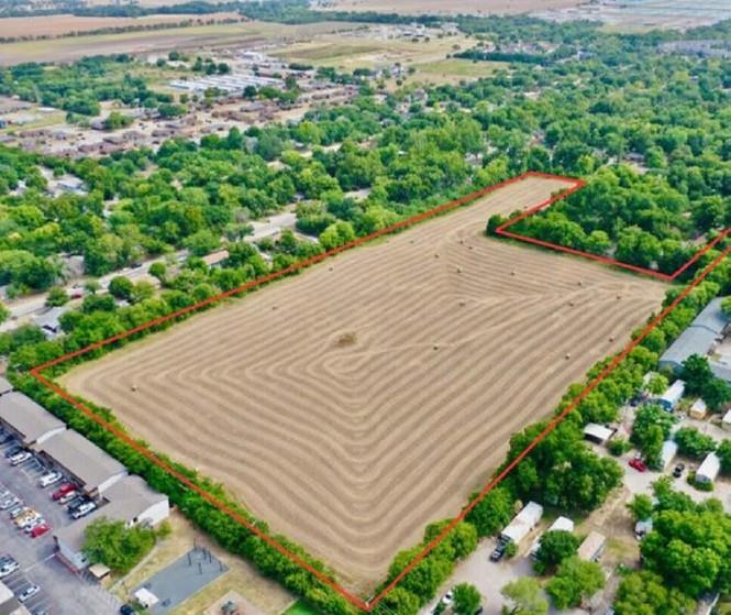A spacious, cleared lot bordered by lush green fo