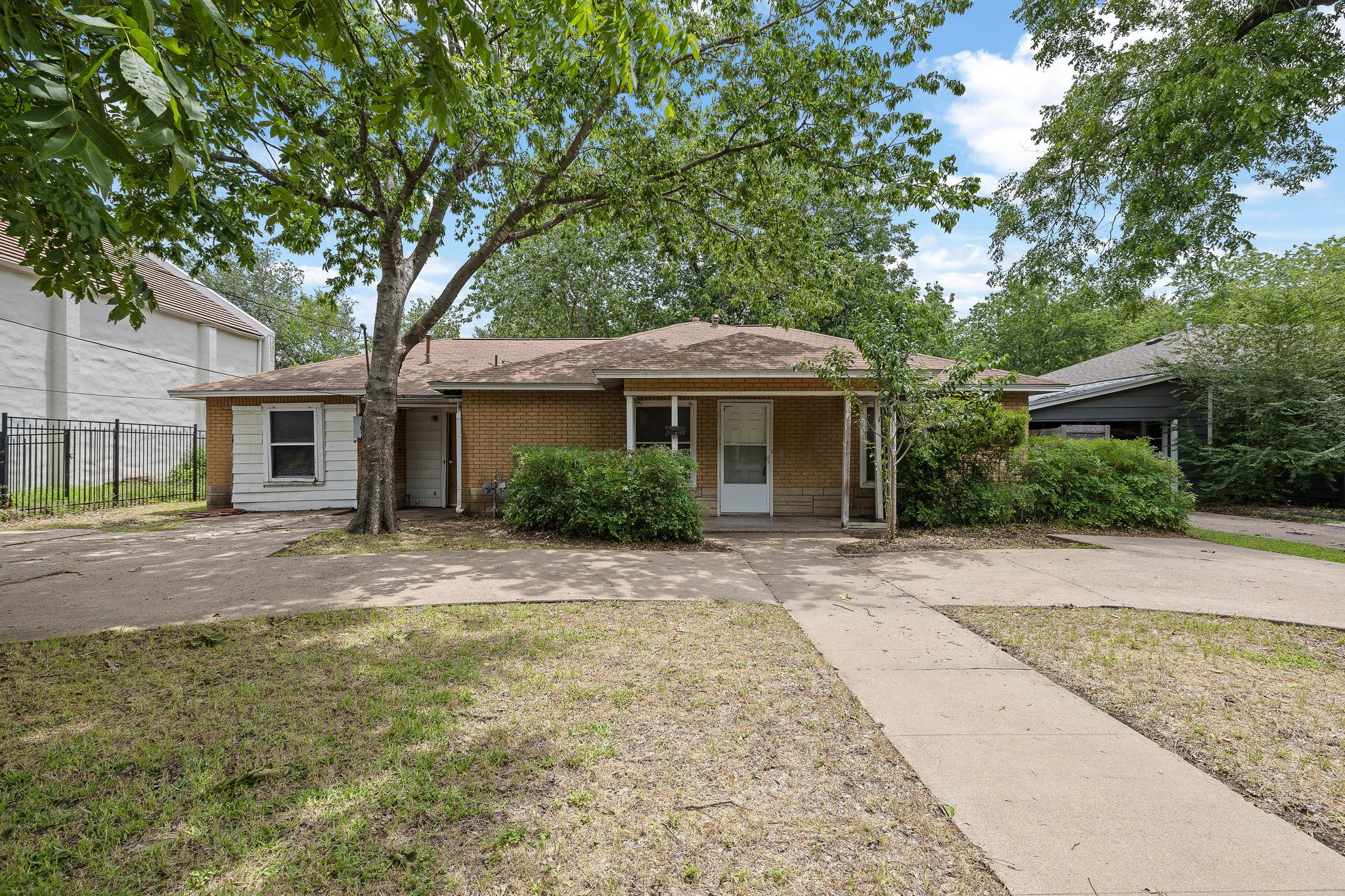 A charming brick exterior with mature trees and a