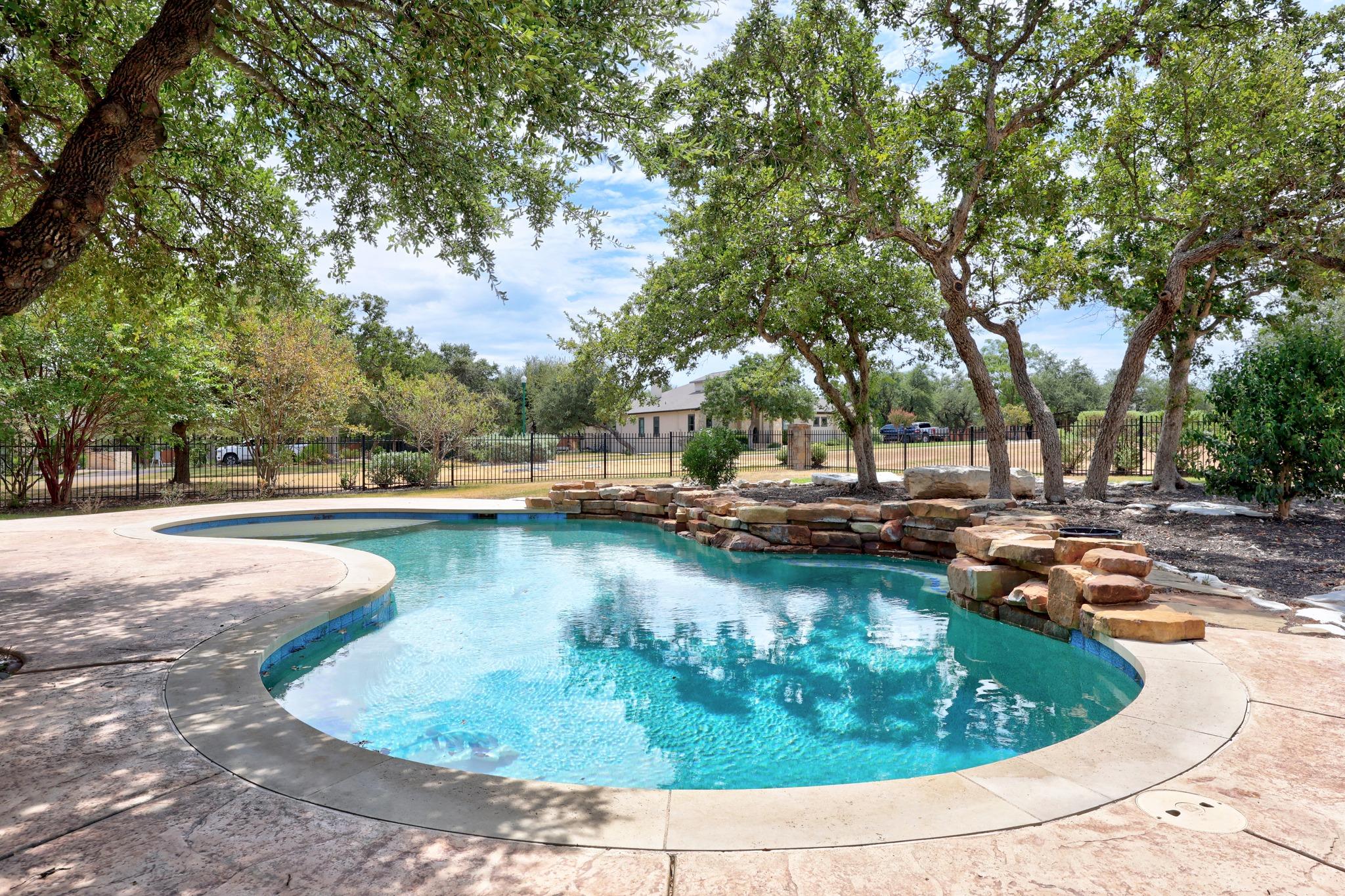Mature trees shade a custom pool area surrounded 