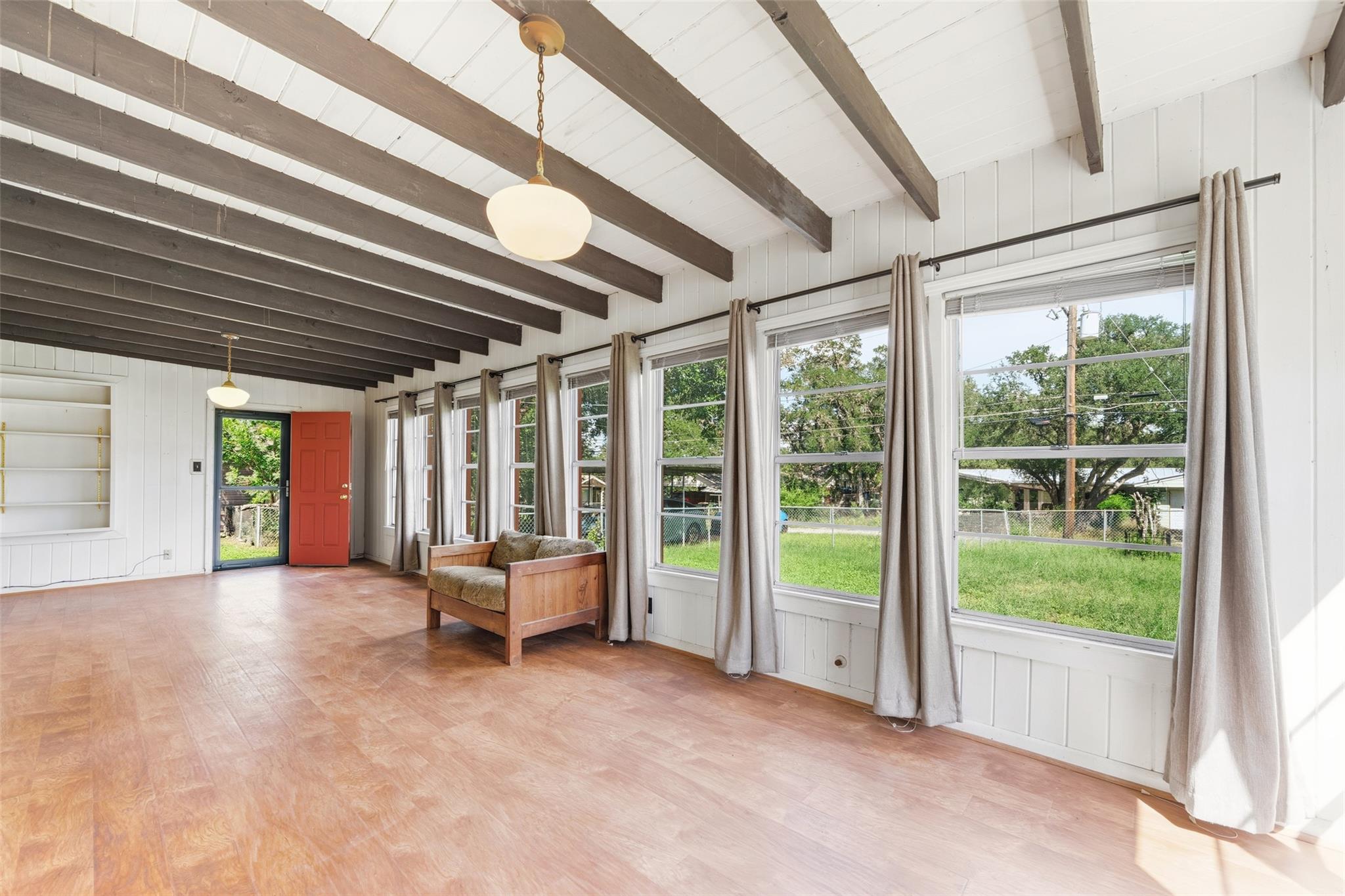 A living area with exposed beams and numerous win