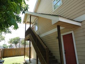 An exterior wooden staircase leads to a covered l