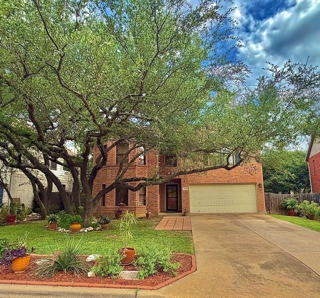 Mature trees frame this brick residence, highligh
