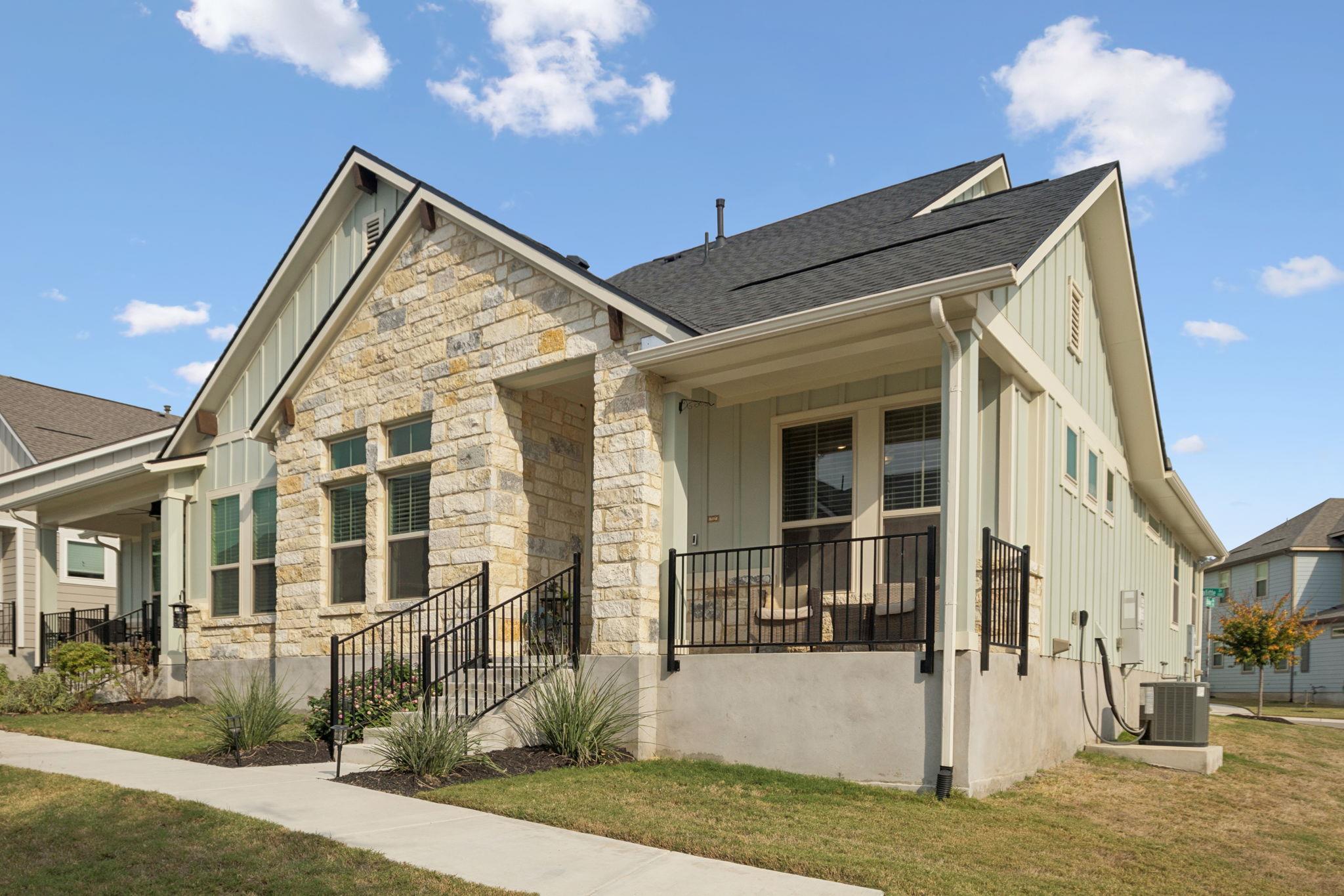 A welcoming front porch with iron railings leads 