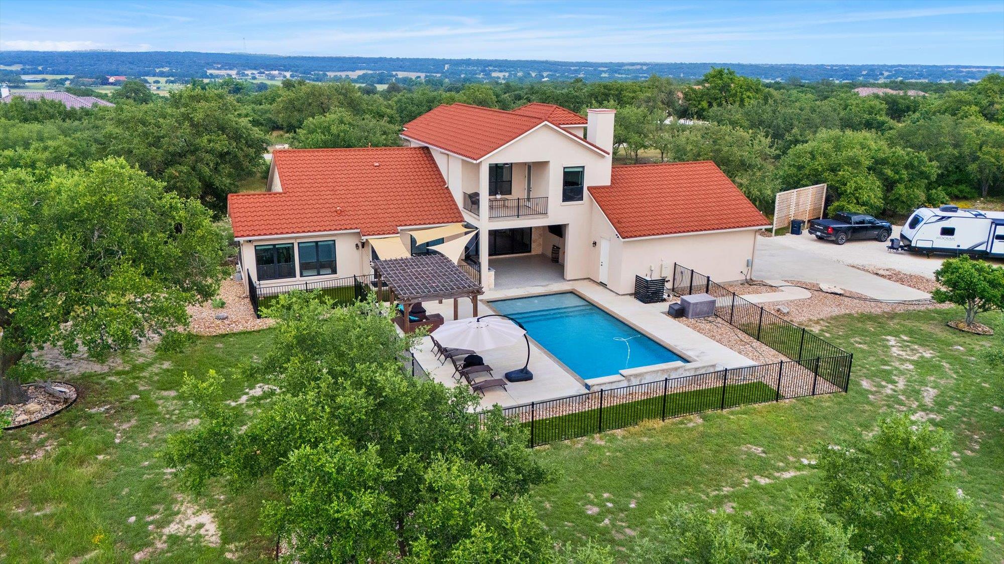 A spacious home with a red tile roof overlooks a 