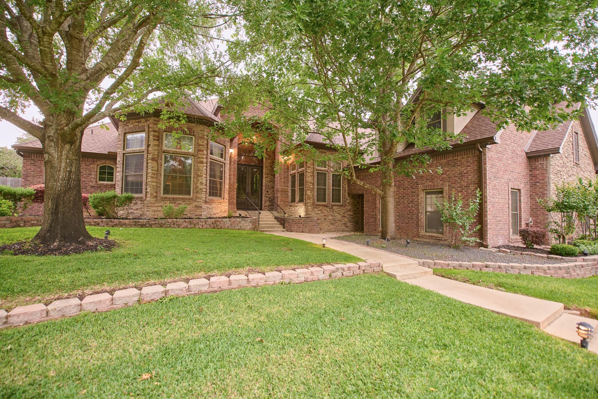 Mature trees frame this brick home, offering shad