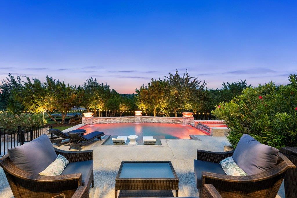 An illuminated backyard oasis awaits with a capti