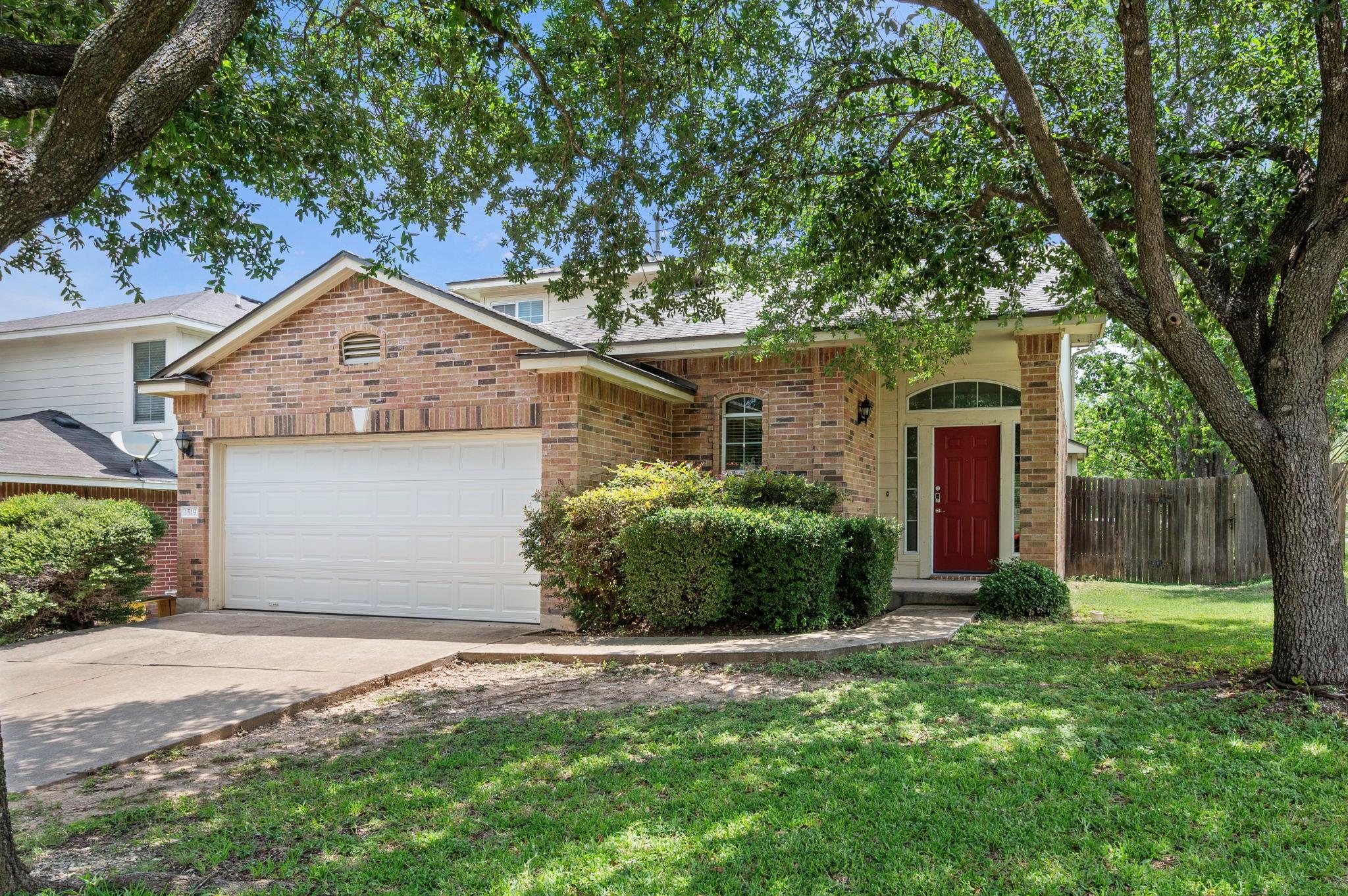A classic brick exterior, shaded by mature trees,