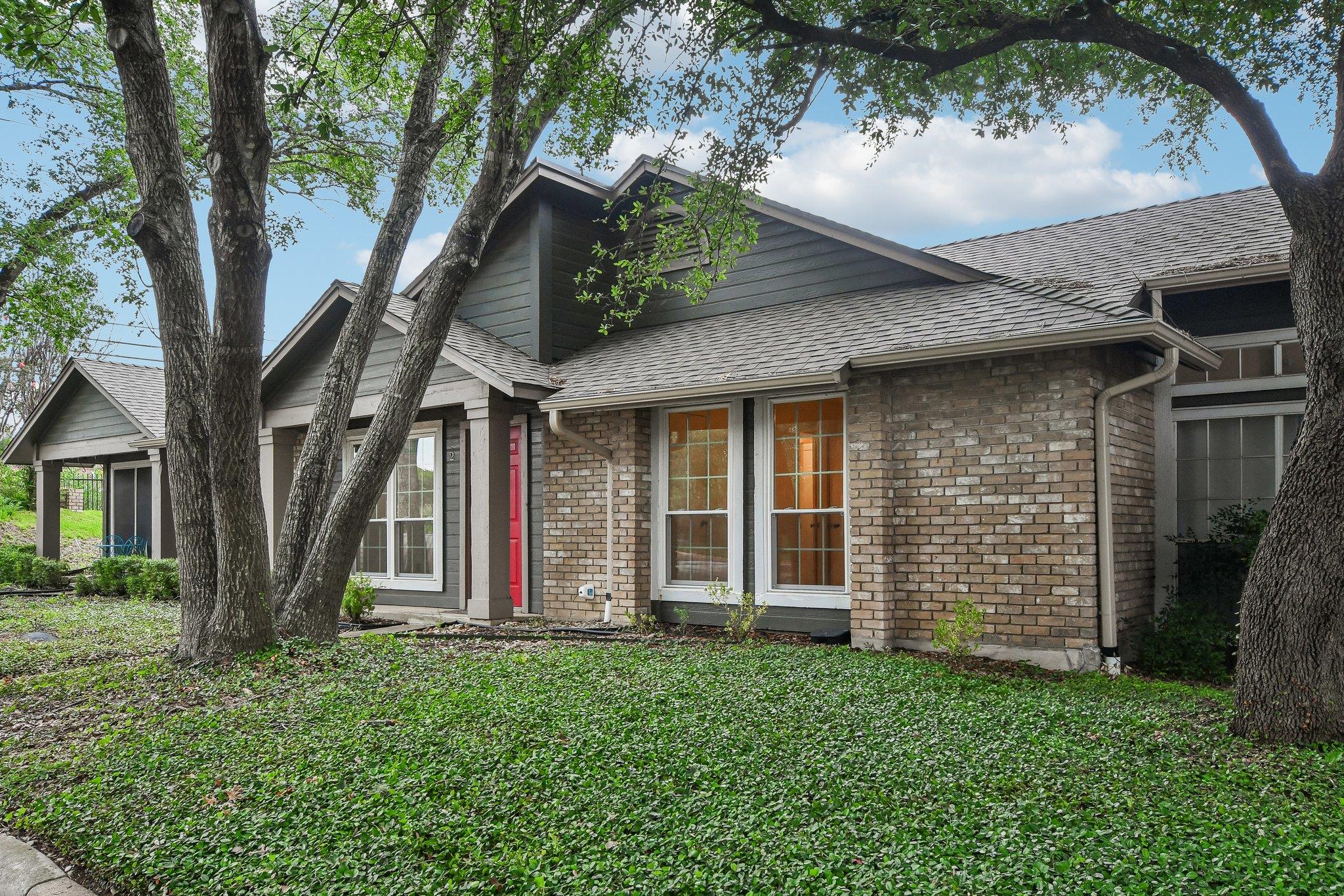Mature trees canopy this inviting brick home with