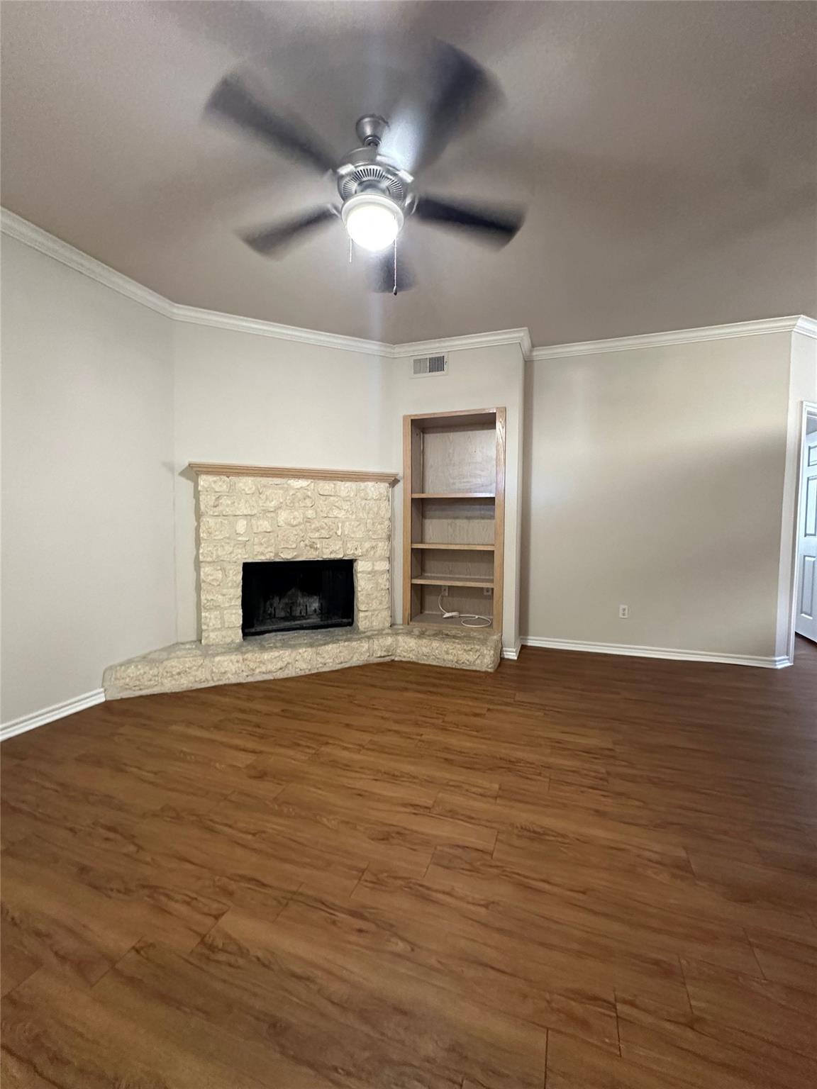 A corner stone fireplace and wood-look flooring e