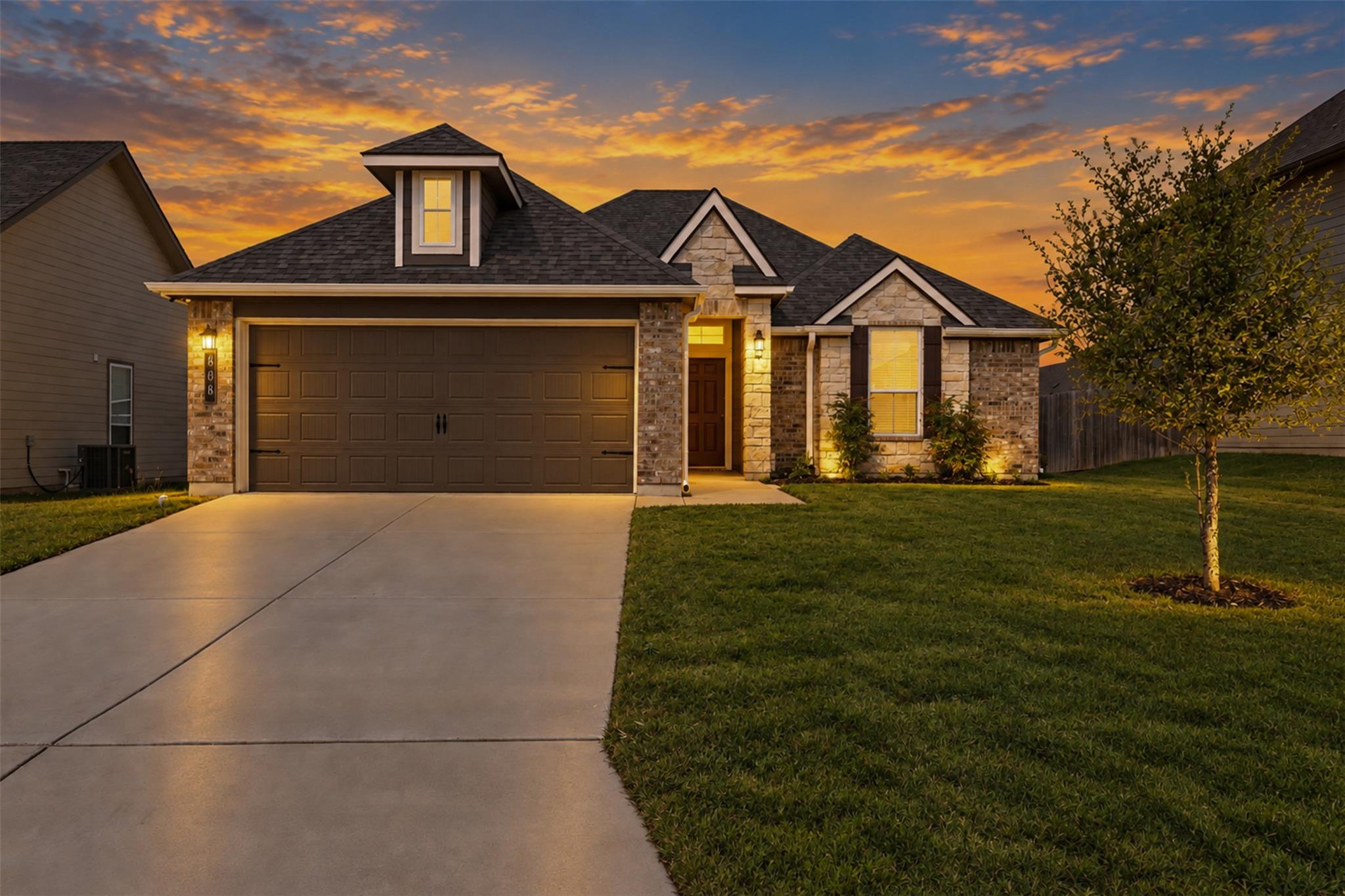 A classic concrete driveway leads to this stone-a
