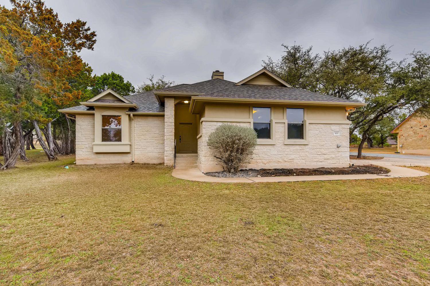 A cream-colored stone facade home with an invitin