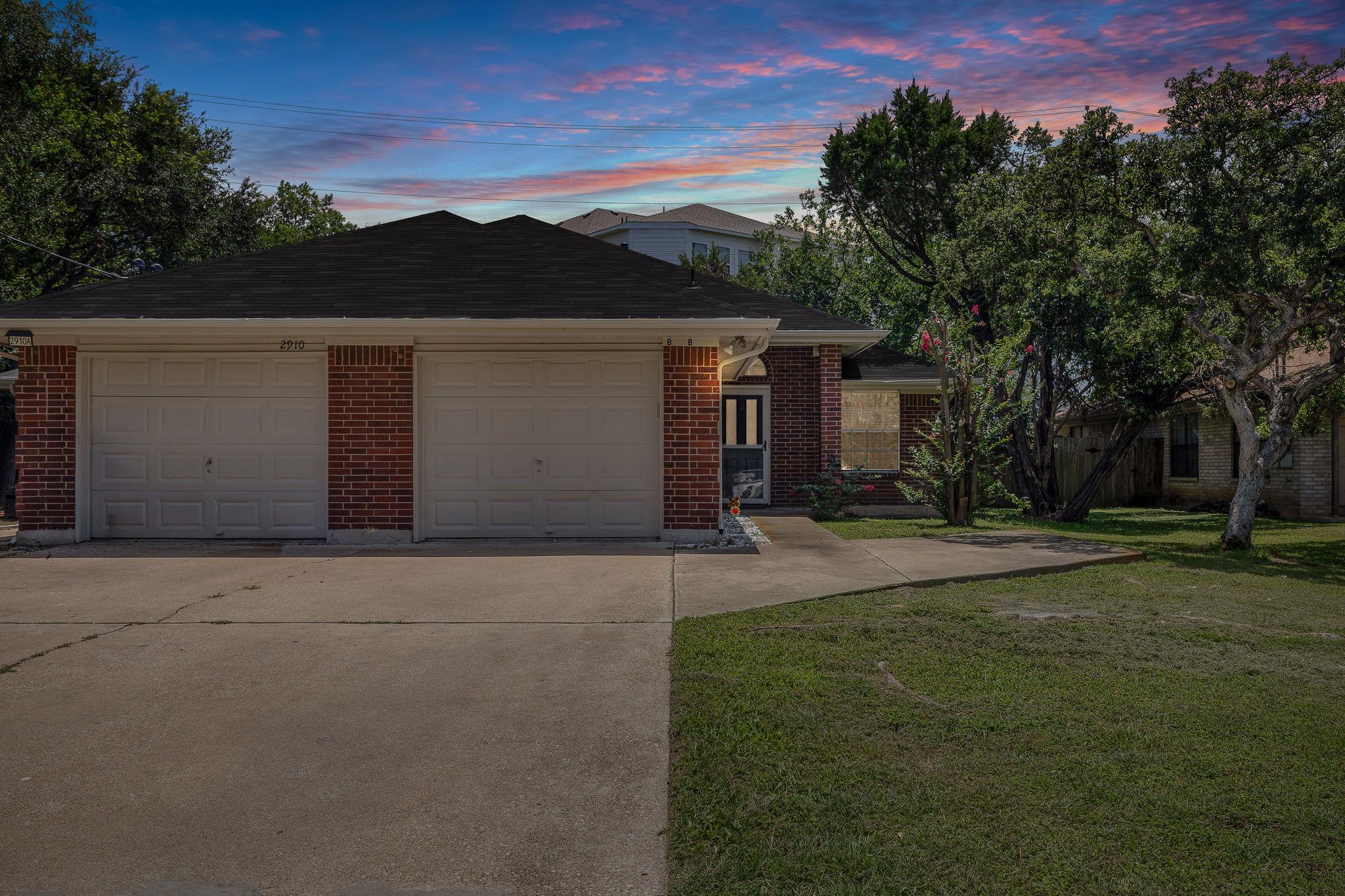 Brick facade and dual garage doors define this we