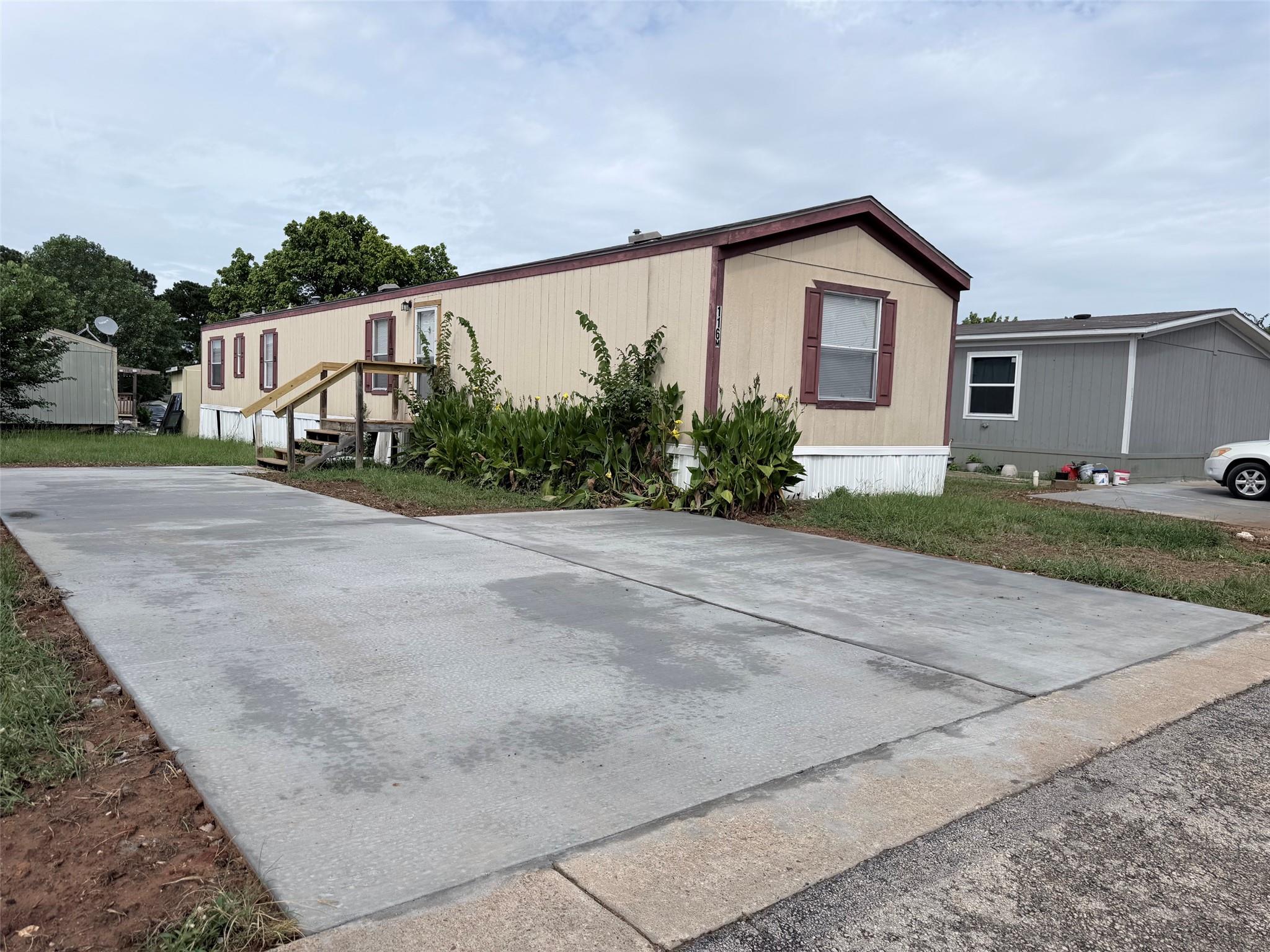Concrete driveway leads to a modest dwelling with