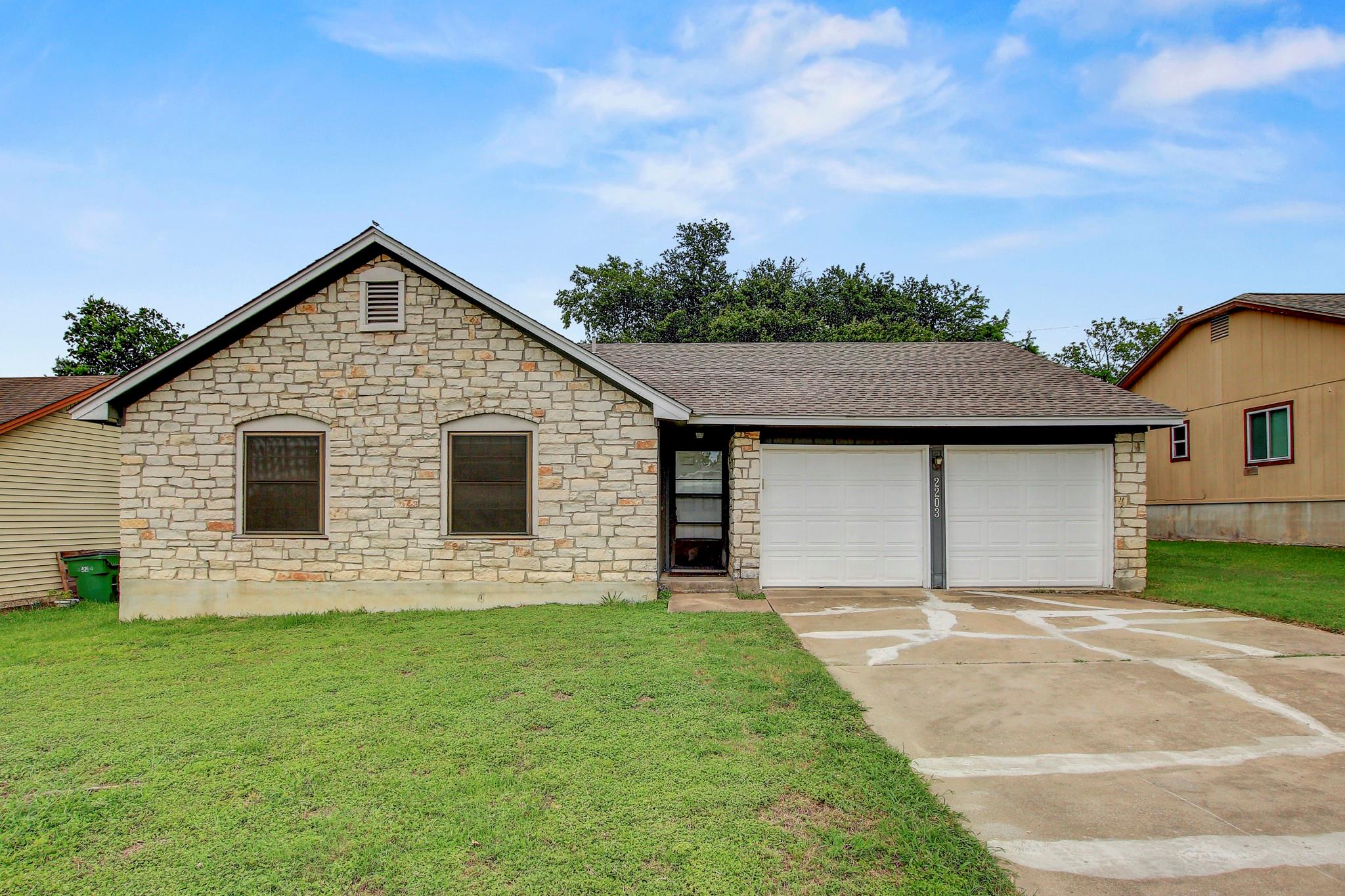 A modest stone-front home with an attached two-ca