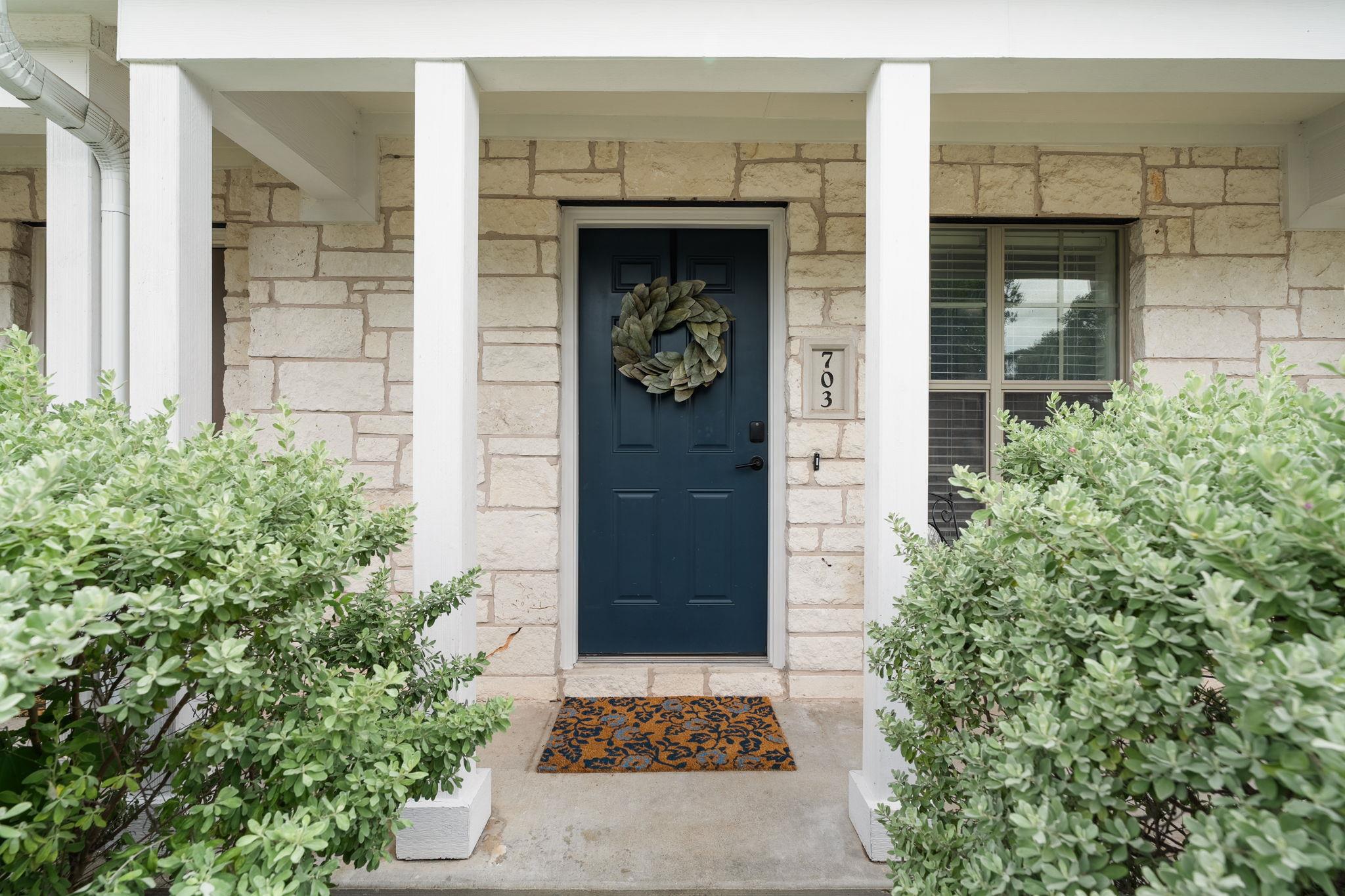 A welcoming entry framed by lush greenery, featur