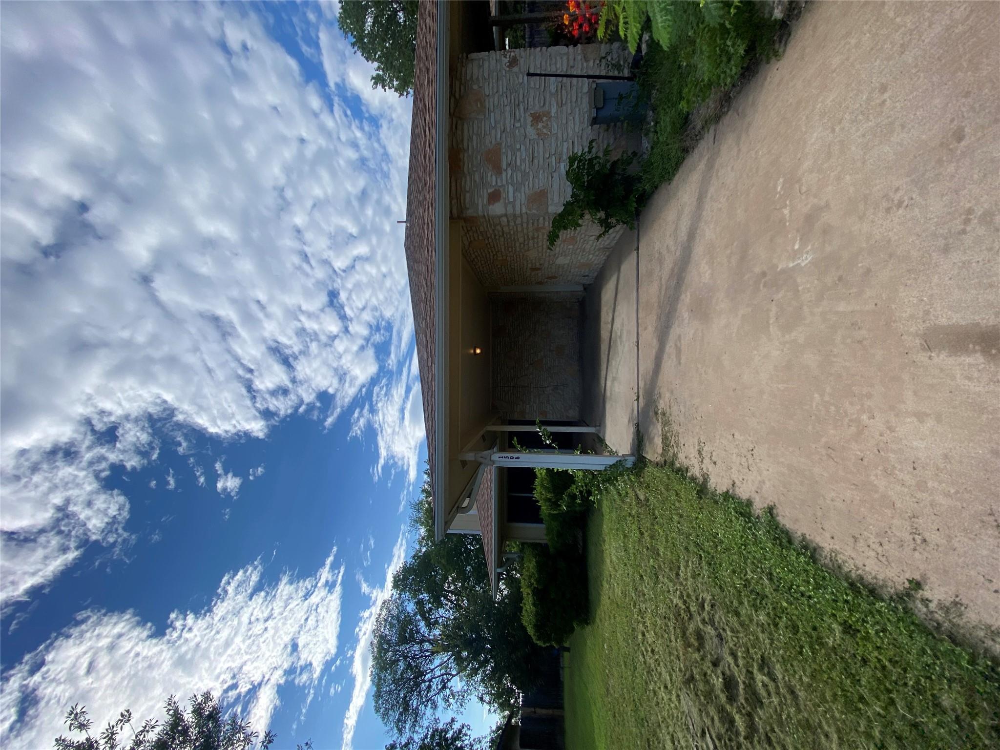 A welcoming driveway leads to a stone and wood si