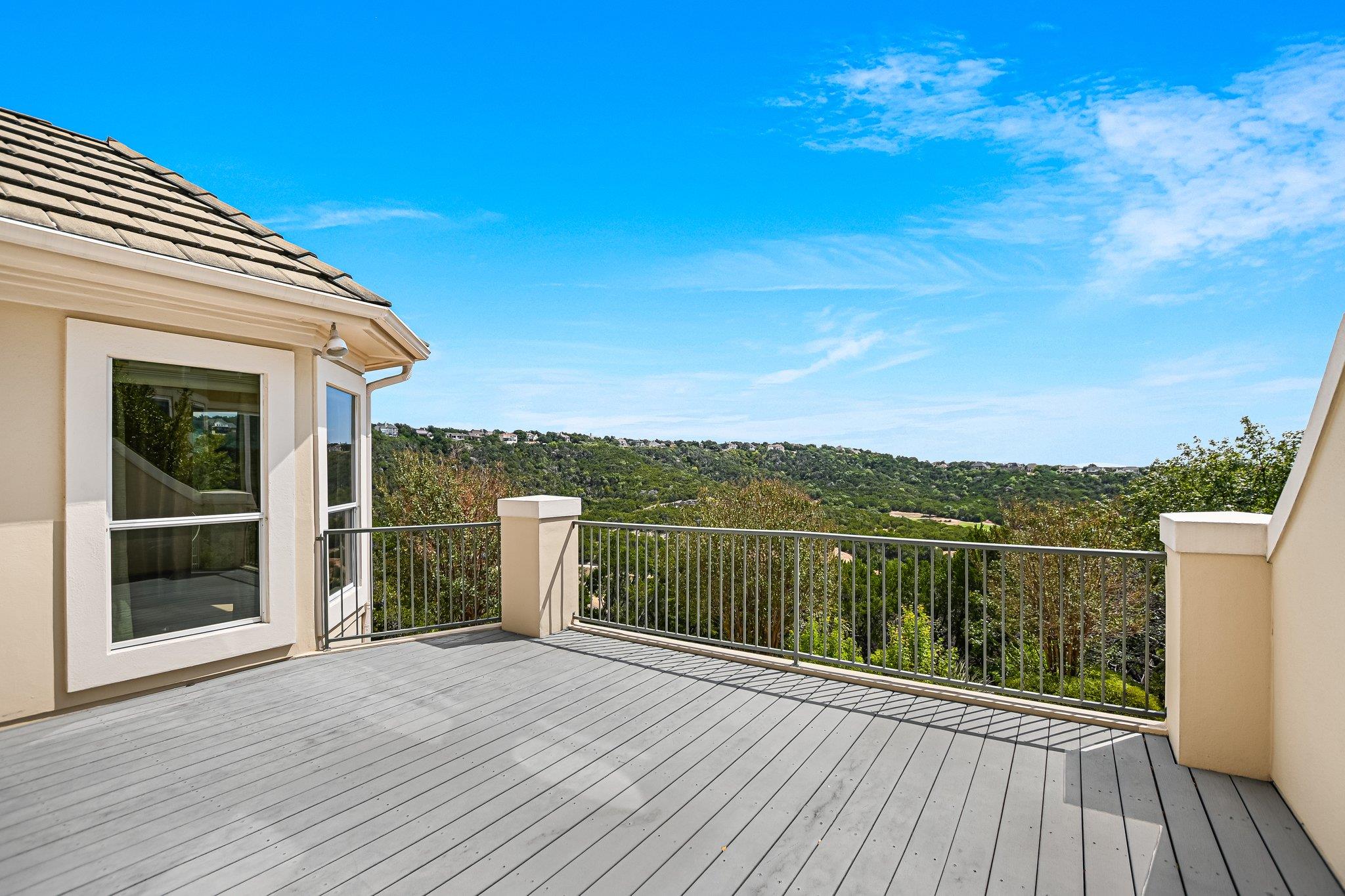 An elevated wood deck overlooks sweeping green hi